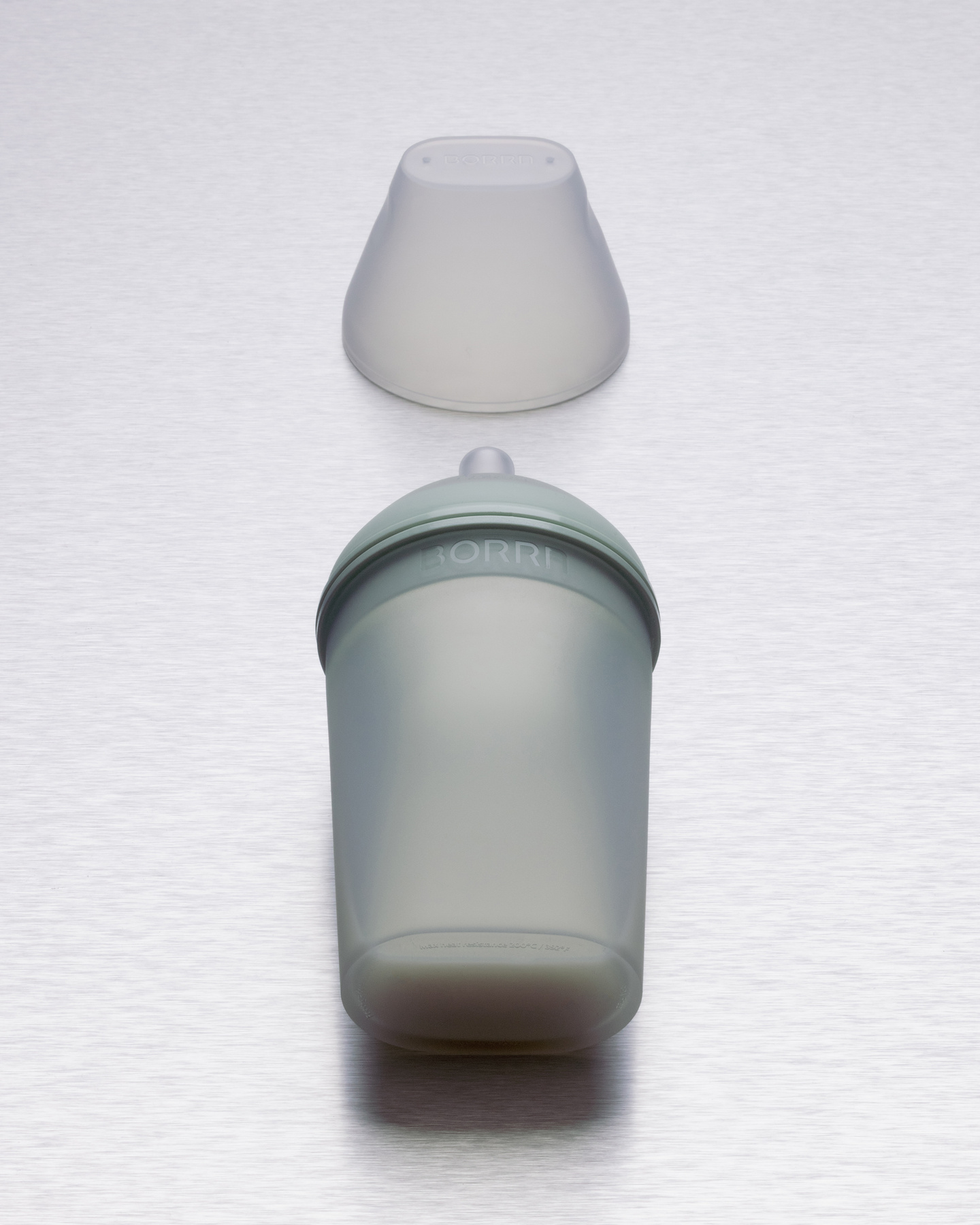 Top-down layout showing disassembled silicone bottle, teat, and protective cap.