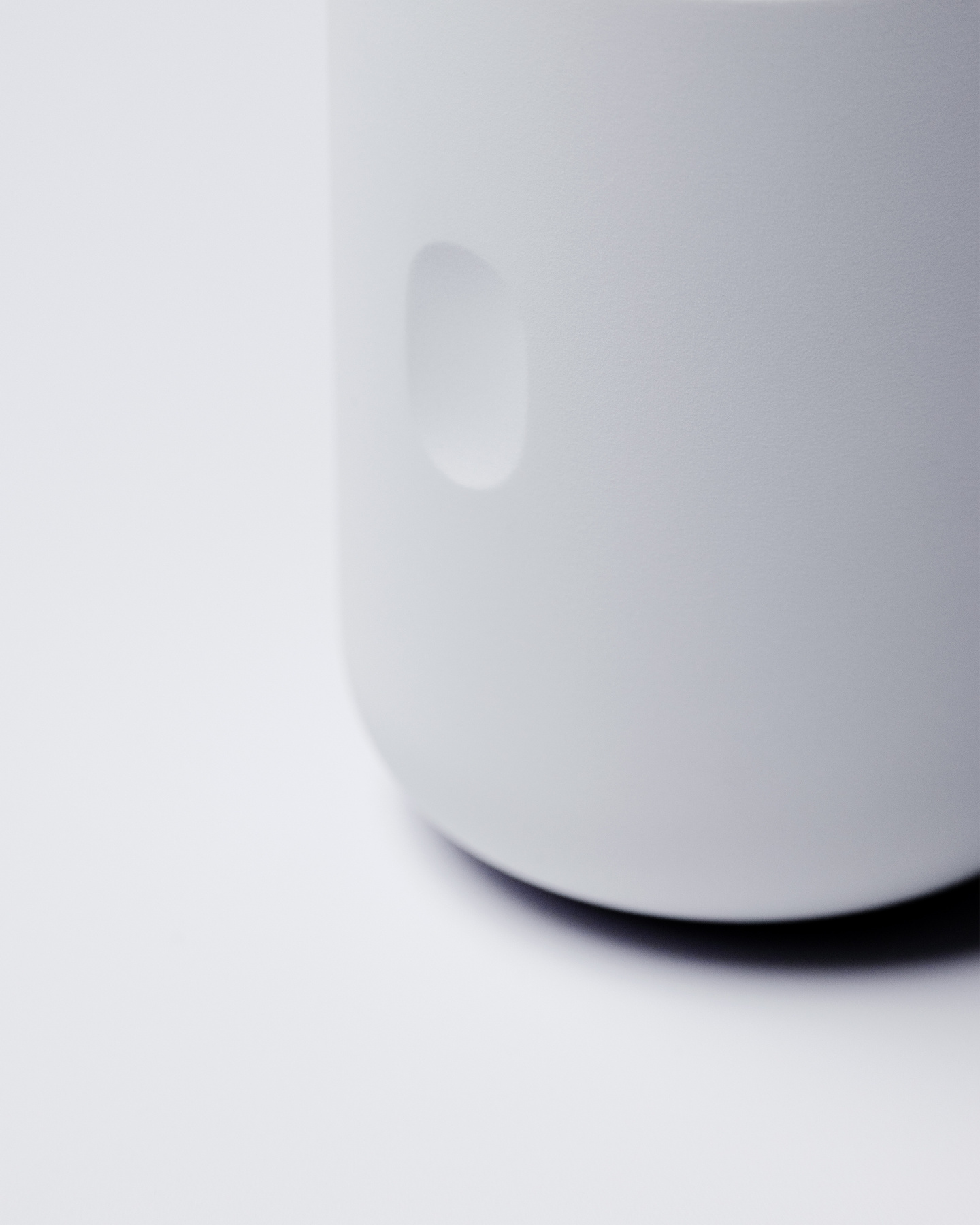 Cropped view of the matte white cylinderical glucose monitor applicator base on a neutral background