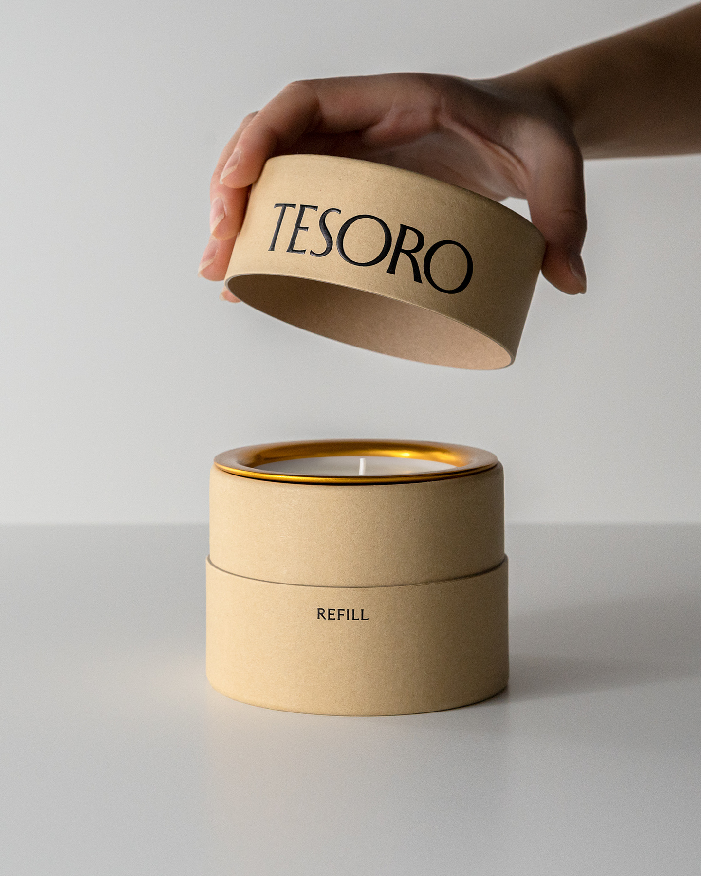 Hand removing lid from cylindrical candle packaging box