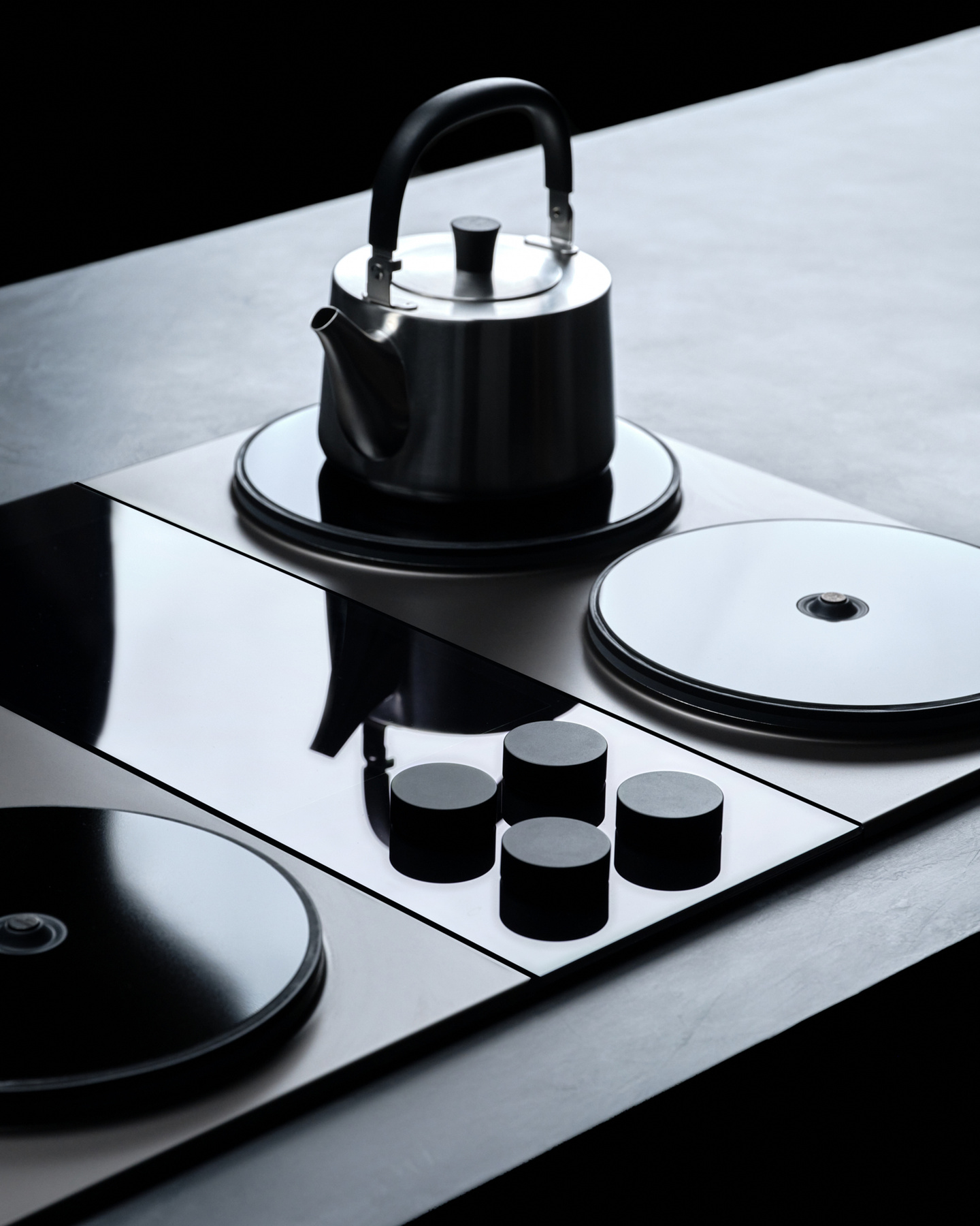Stainless steel kettle resting on a dark induction stovetop burner