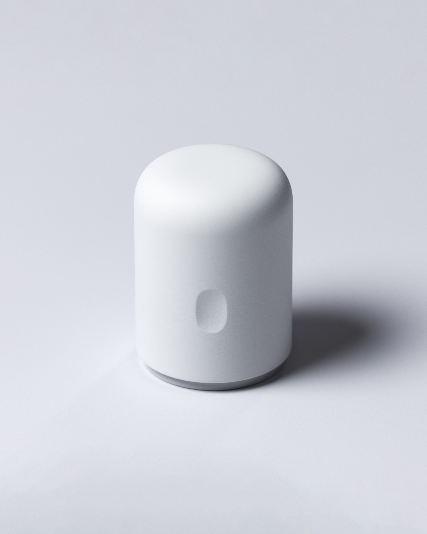 Matte white cylindrical continuous glucose monitor applicator standing upright on a neutral background