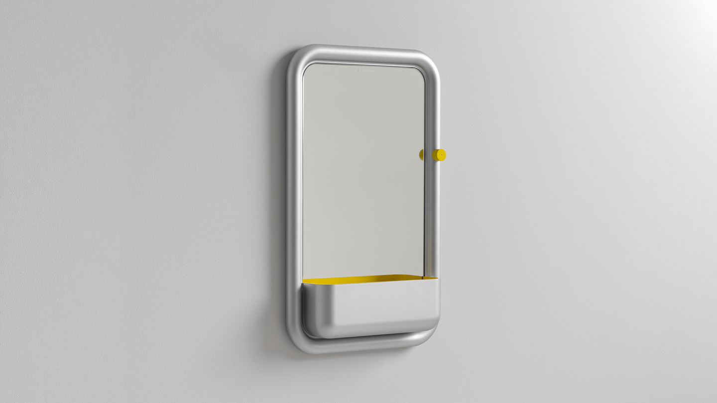 Wall-mounted rectangular mirror unit with a yellow dial dial accent and lower tray on a light wall