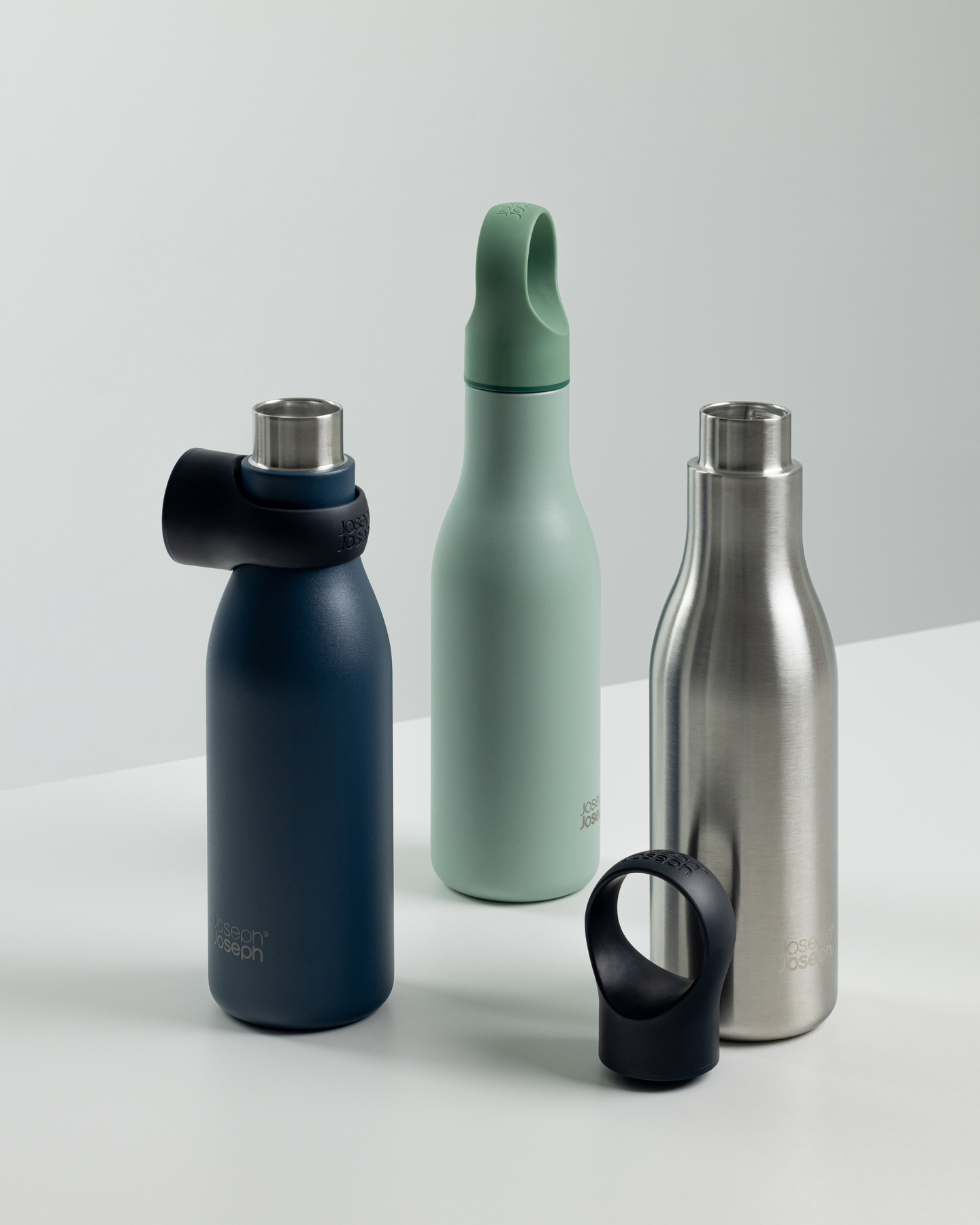 Four reusable water bottles in different colors and finishes standing together