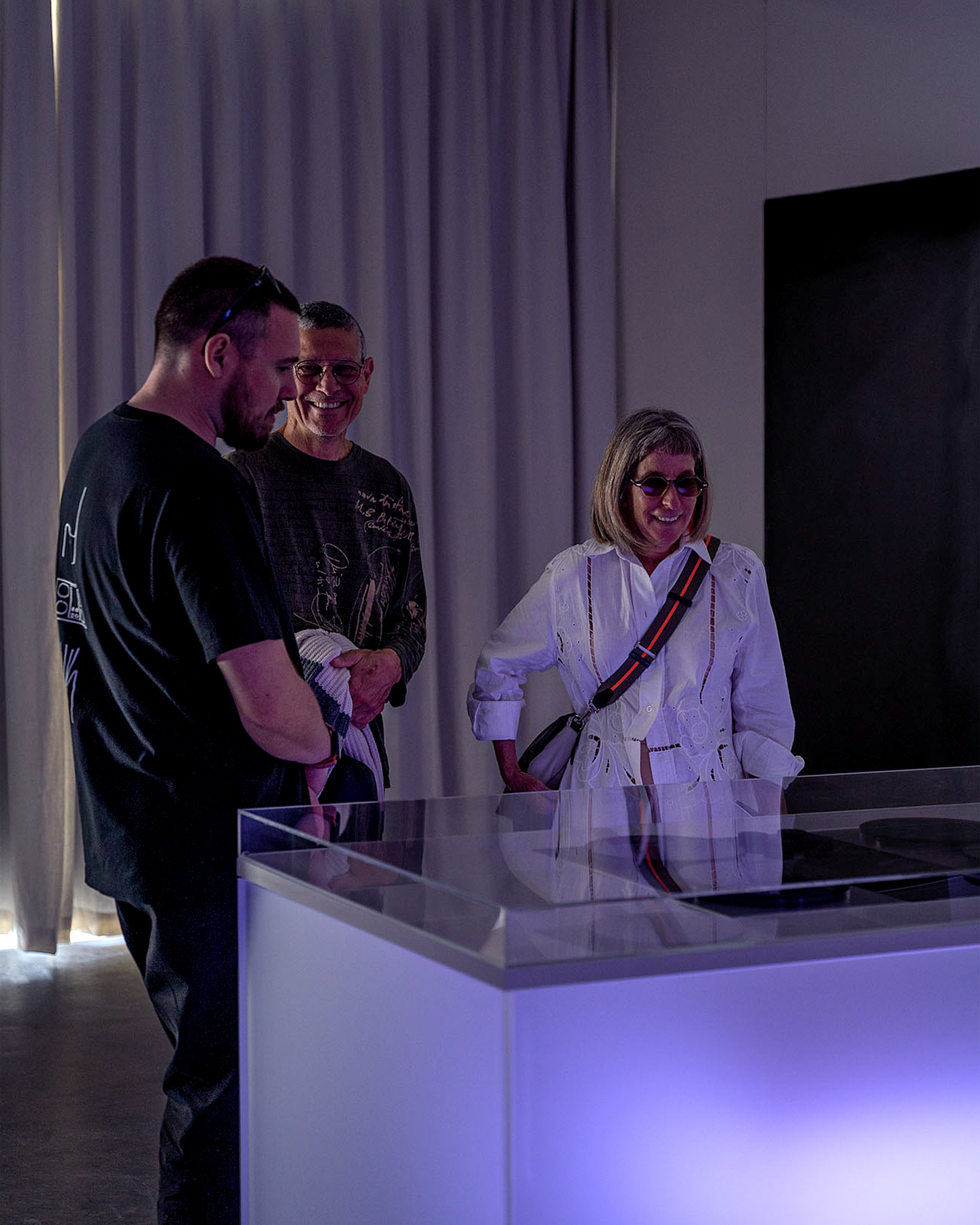 Visitors standing beside an illuminated exhibition counter examining products.