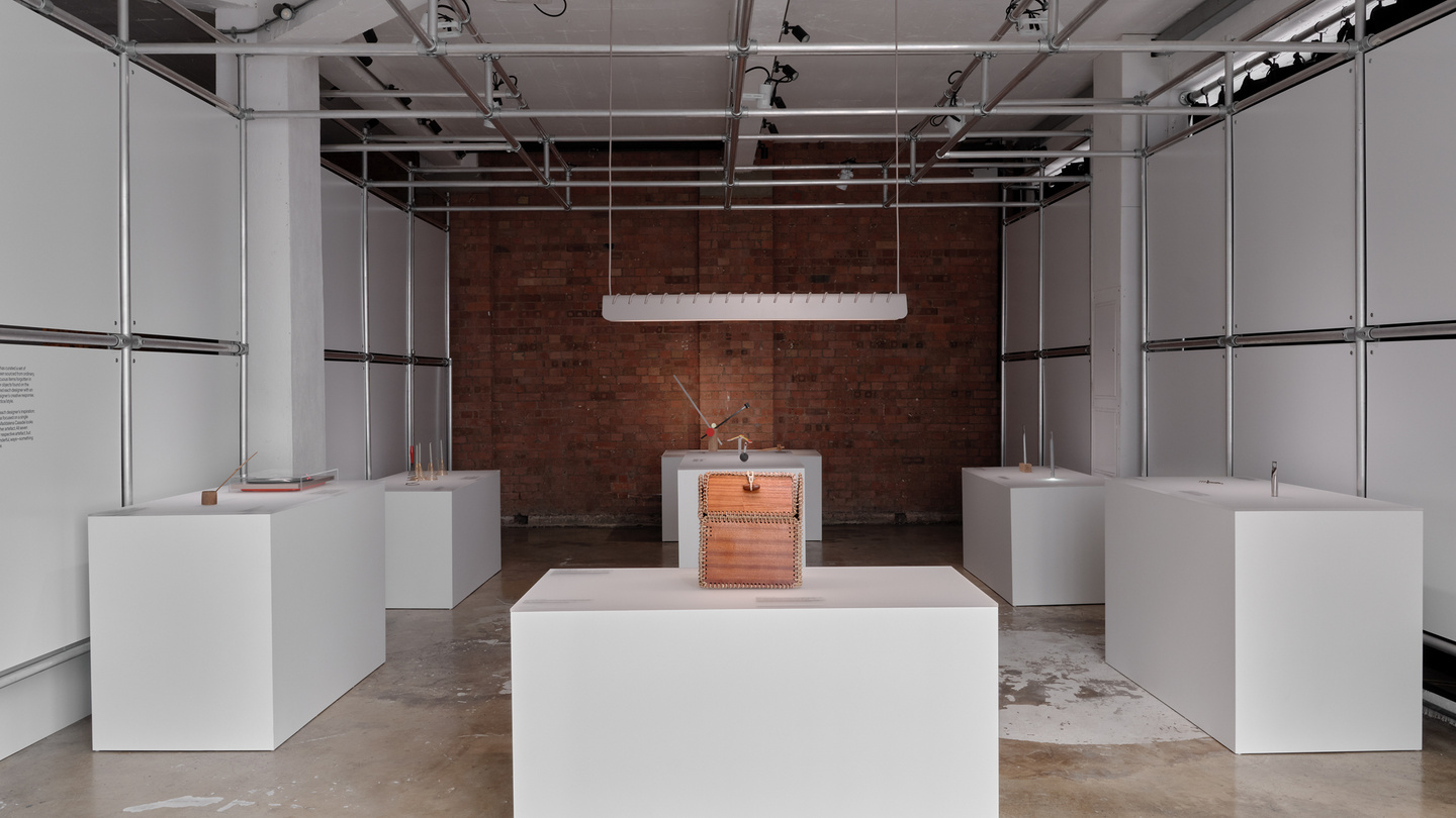 View of gallery space with white display plinths and brick wall backdrop