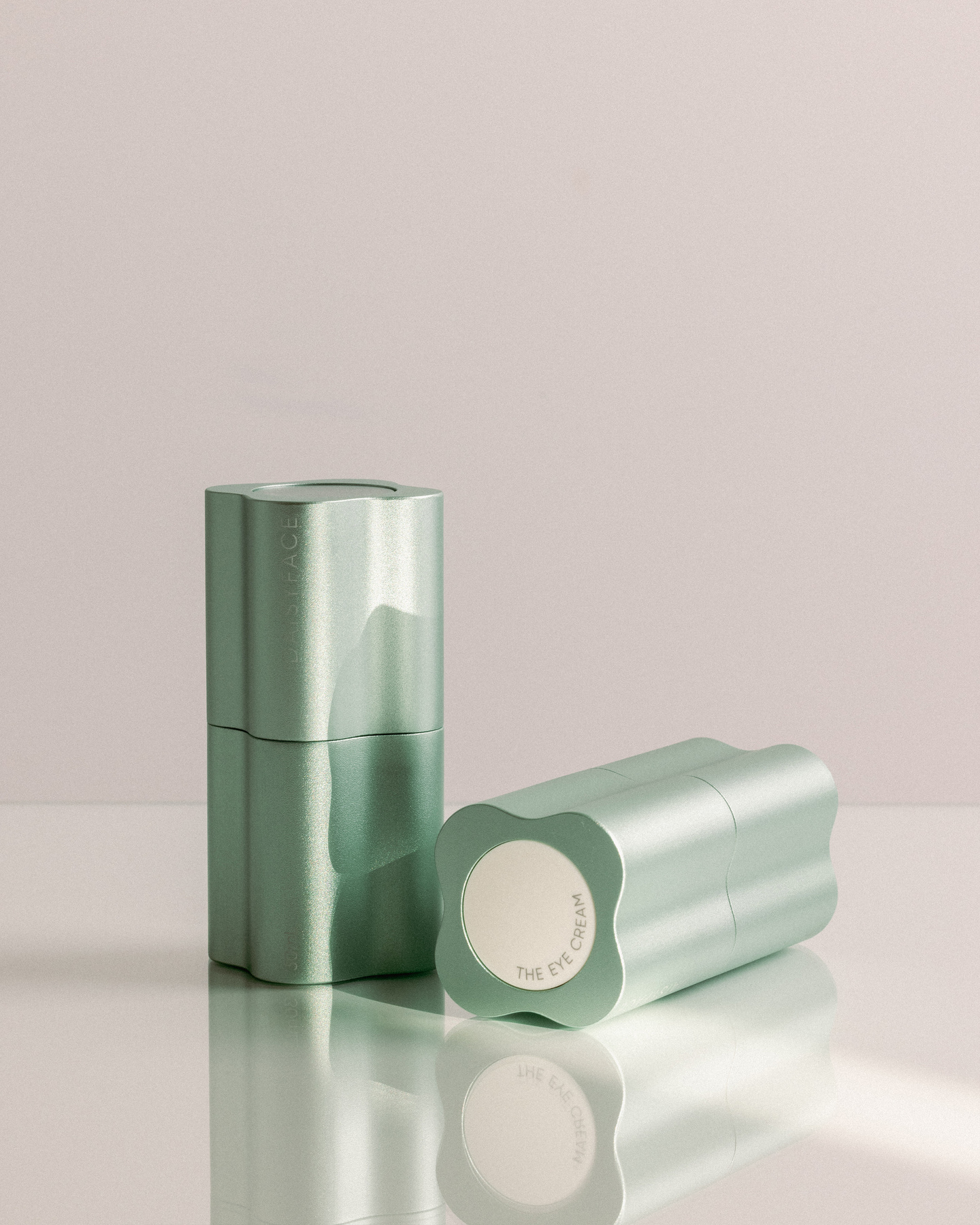 Two green skincare bottles reflecting on a bright surface