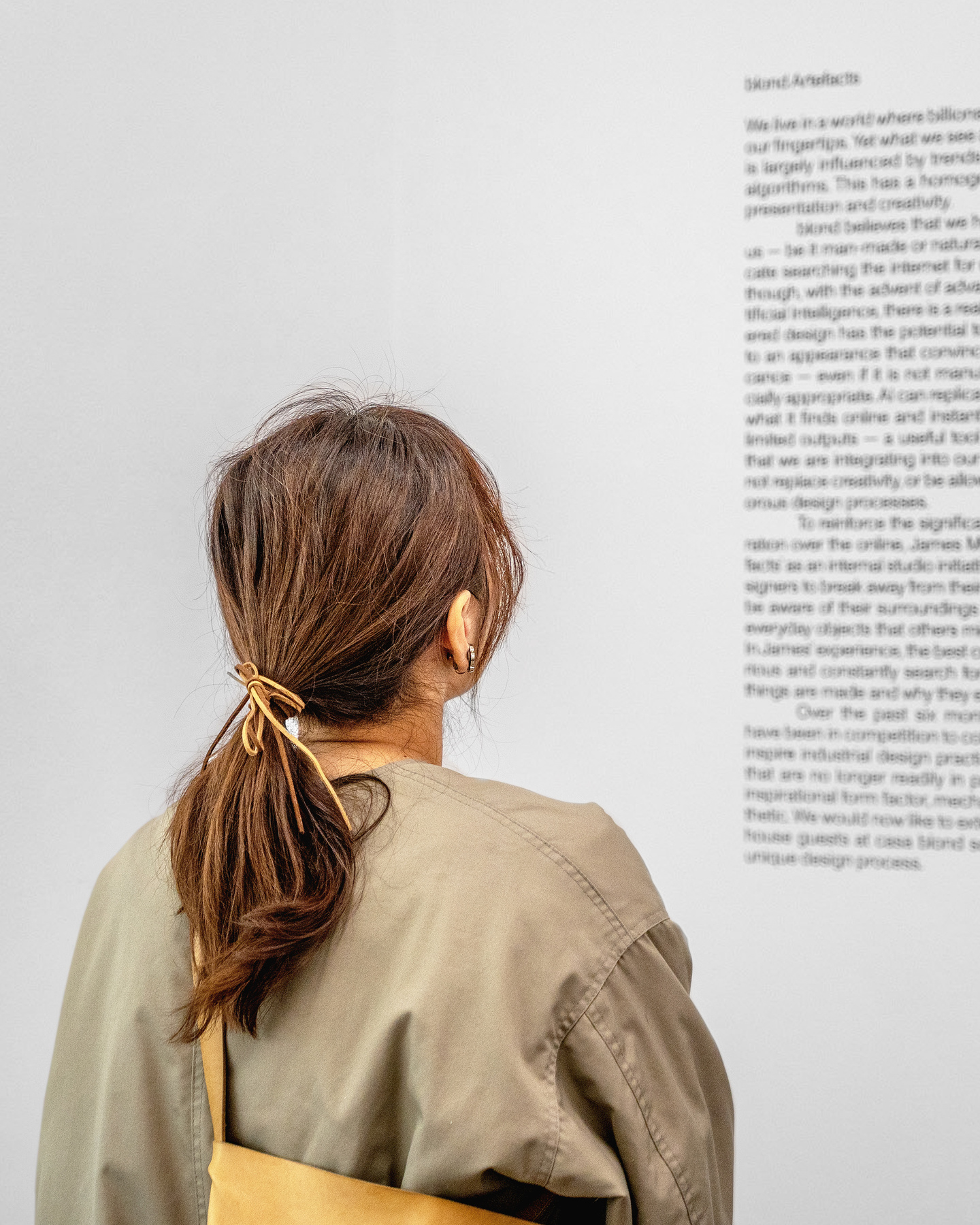 Visitor standing in front of a white gallery wall reading exhibition text.