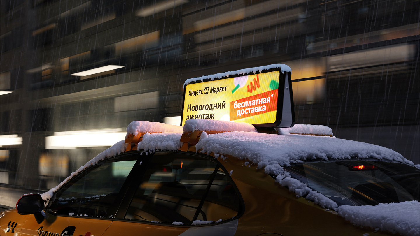 Yellow taxi parked on a snow-covered city street at night with glowing rooftop sign