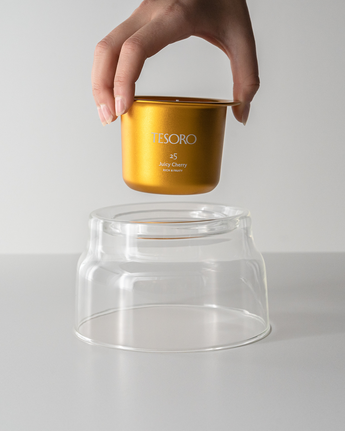 Hand placing a gold metal candle refill insert into a clear glass jar