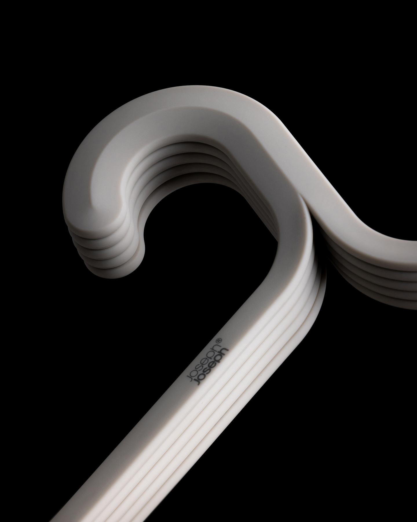 Close-up view of stacked grey coat hanger necks against a black background