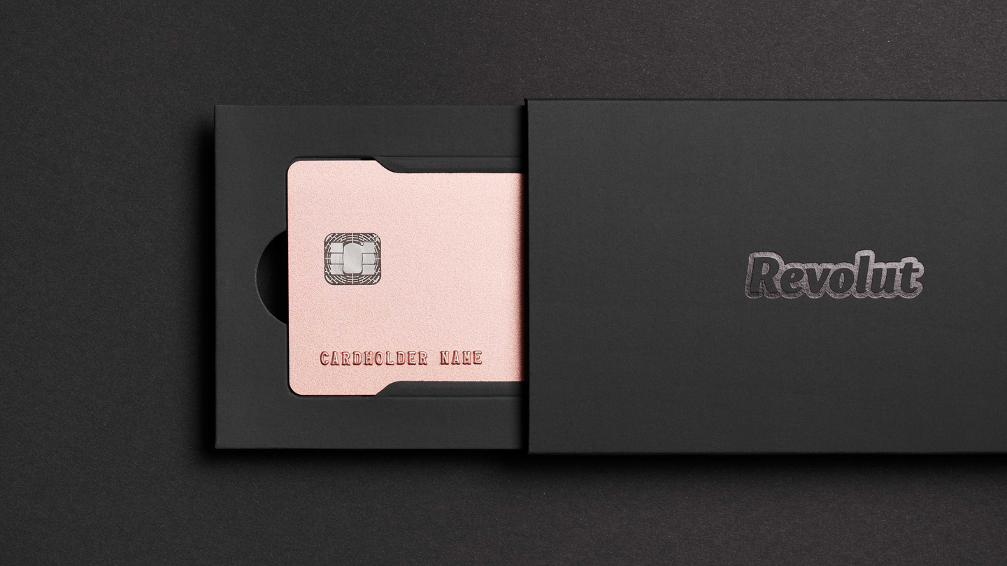 Rose gold Revolut card sliding out of a black sleeve box.
