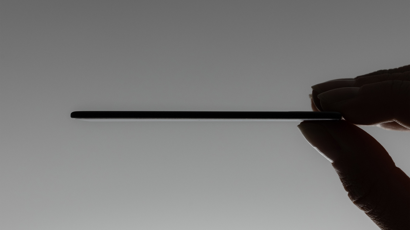Side profile silhouette of a hand holding a thin card tracker horizontally.