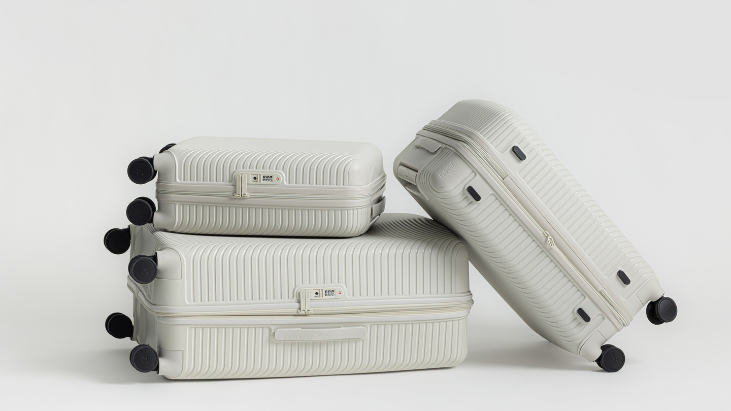 White hardshell suitcases stacked at an angle on a light surface