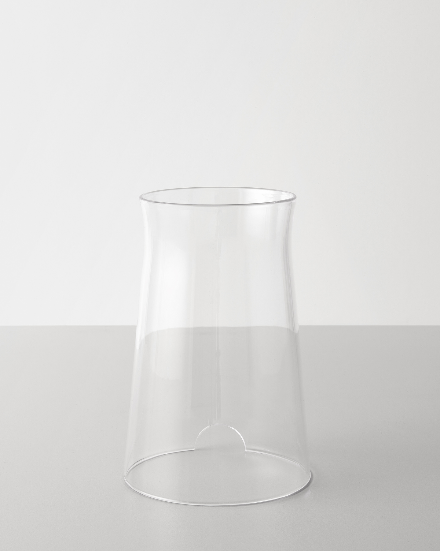 Clear glass cylindrical container resting on a plain white surface.