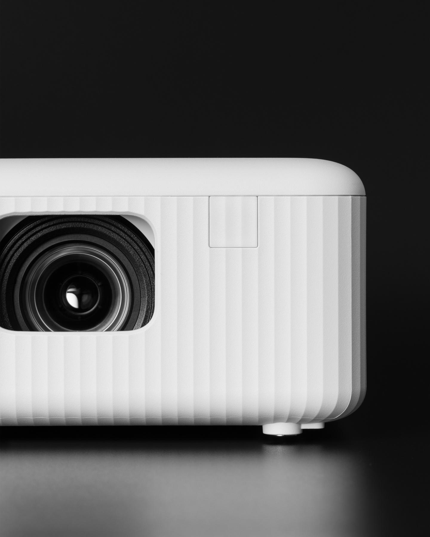 Front corner view showing lens and ribbed body of white projector