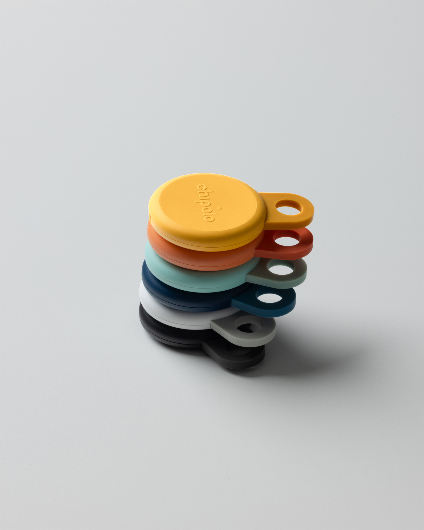 Stack of small round Chipolo Loop trackers in various colors on a white background.