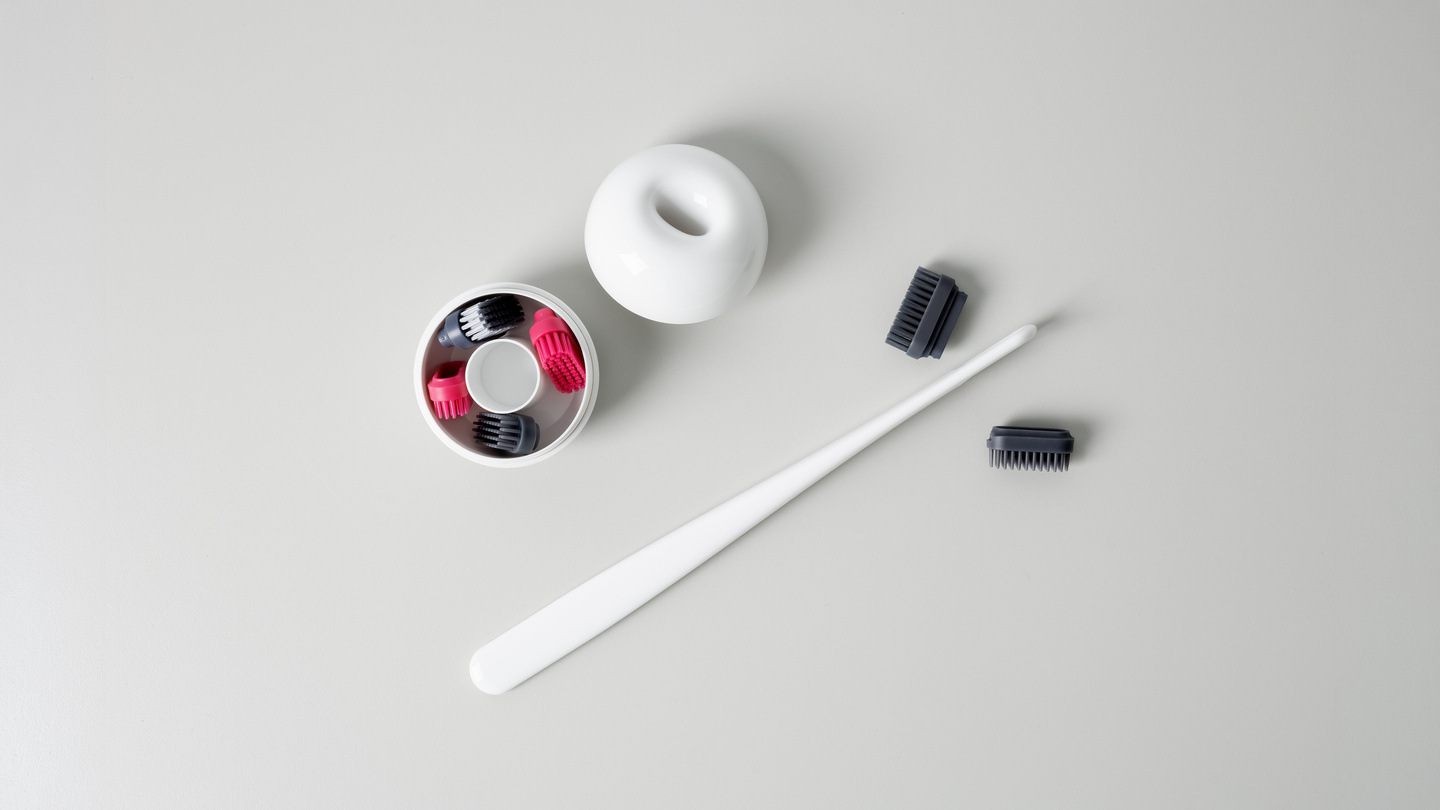 Overhead view of a white hair styling tool, base, and colored attachment heads