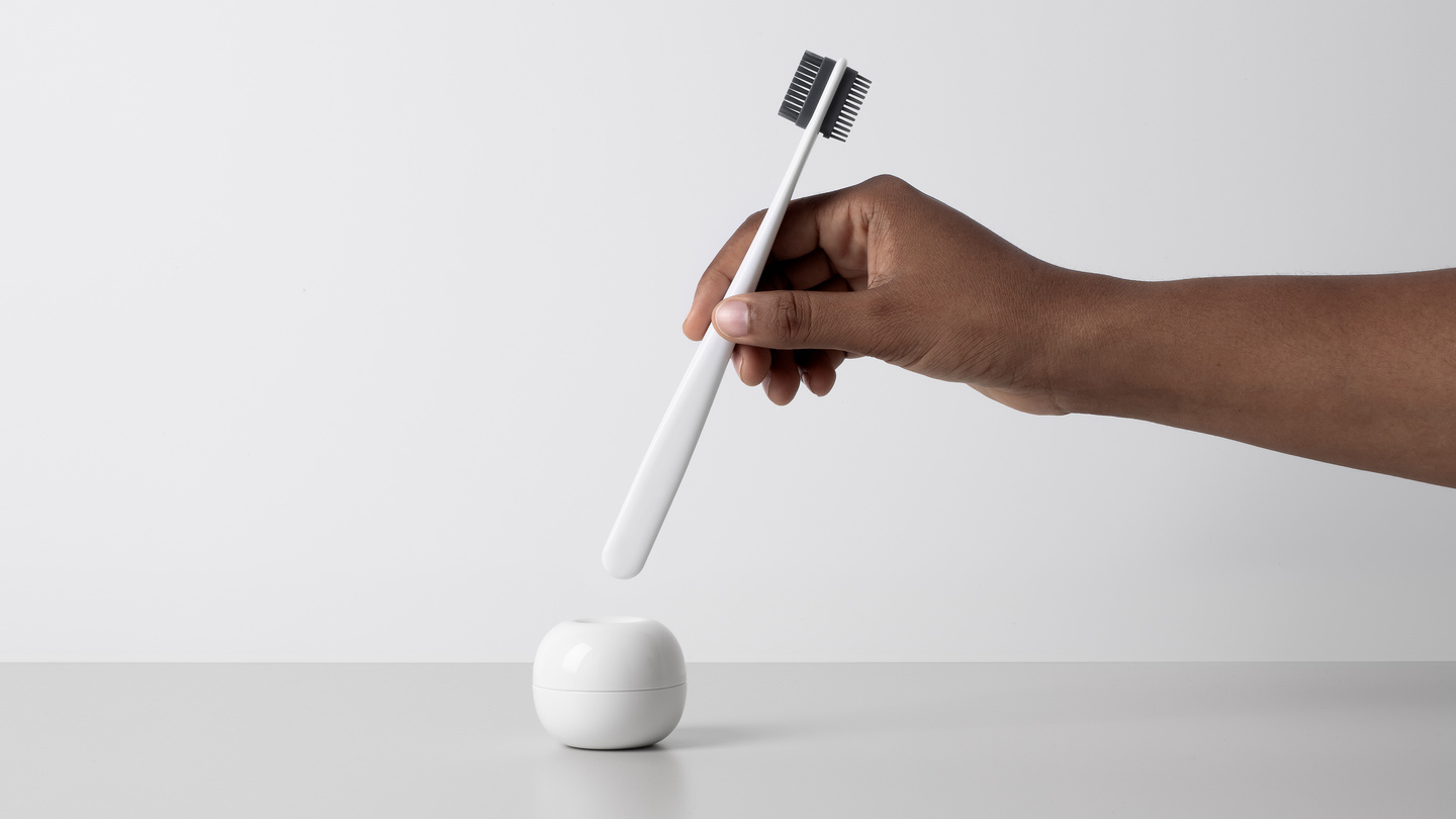 Hand placing a white hair styling tool into a rounded base unit