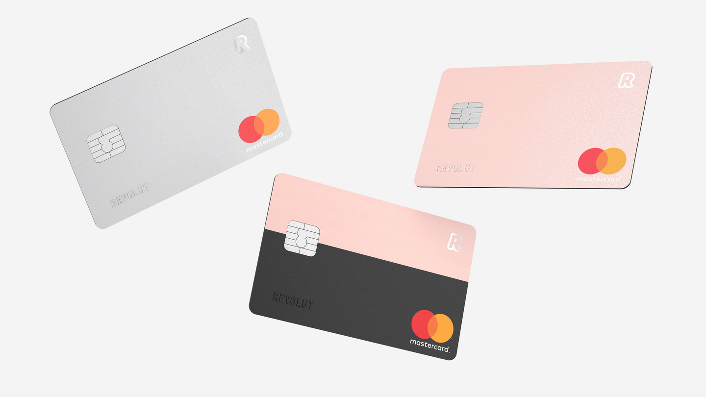 Silver, rose gold, and black Revolut bank cards displayed on a light surface.