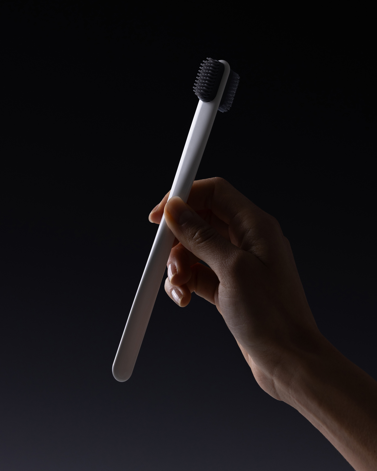 Hand holding a slender hair styling tool against a dark background