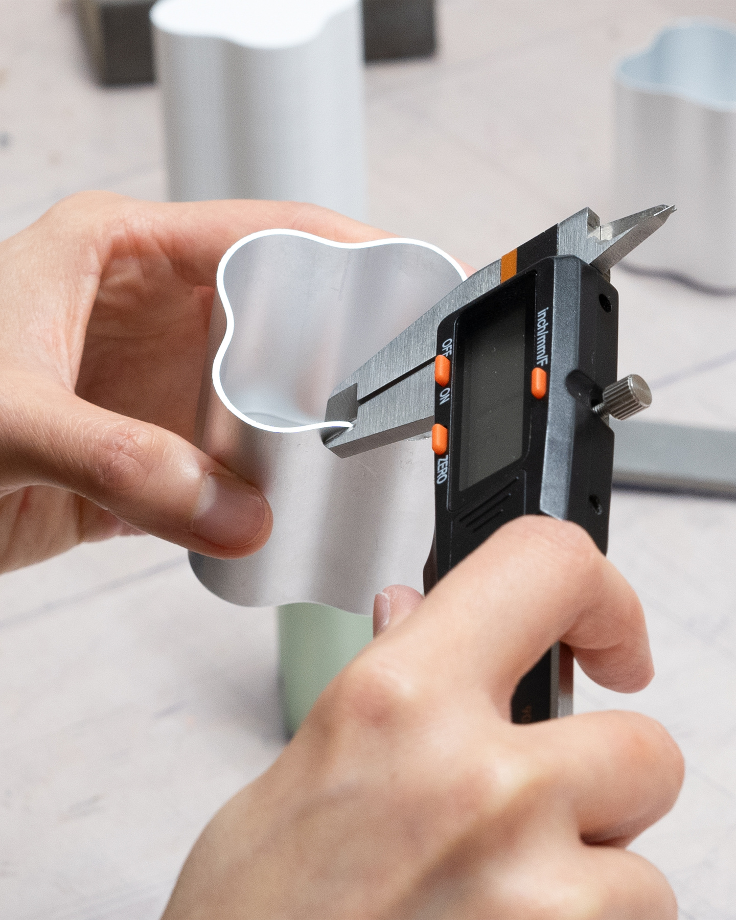 Hands using calipers to measure a prototype bottle component