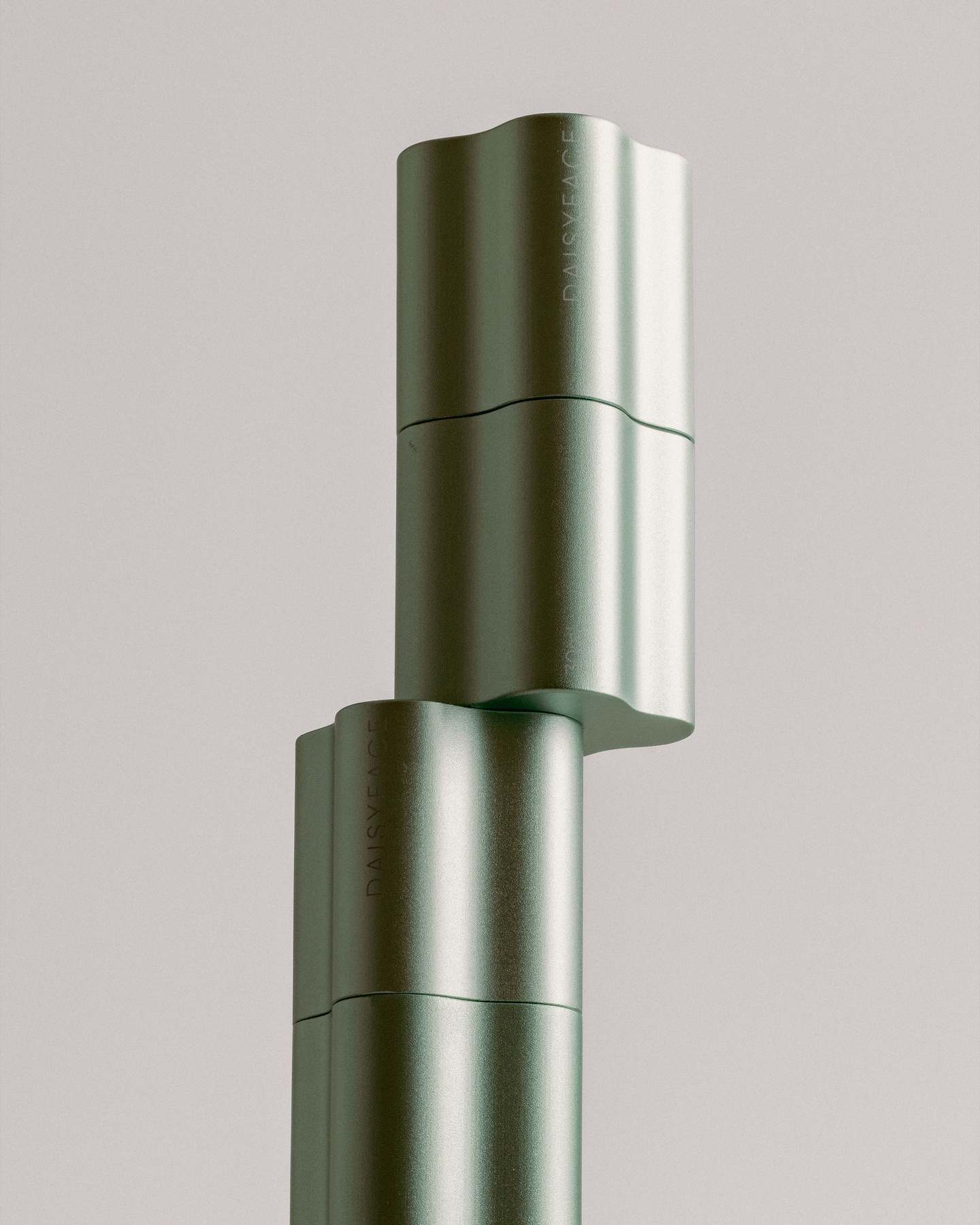 Two metallic green fluted skincare bottles stacked vertically