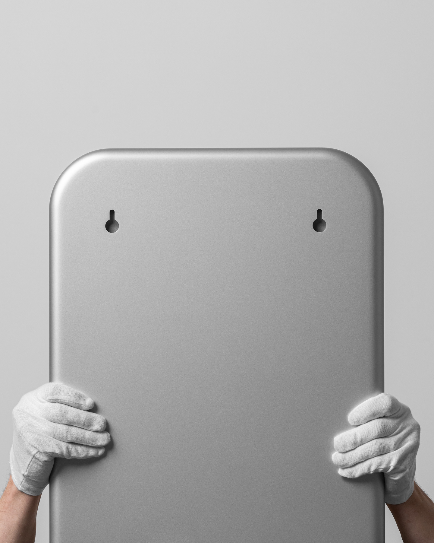 Hands wearing white protective gloves holding up a rectangular metallic frame