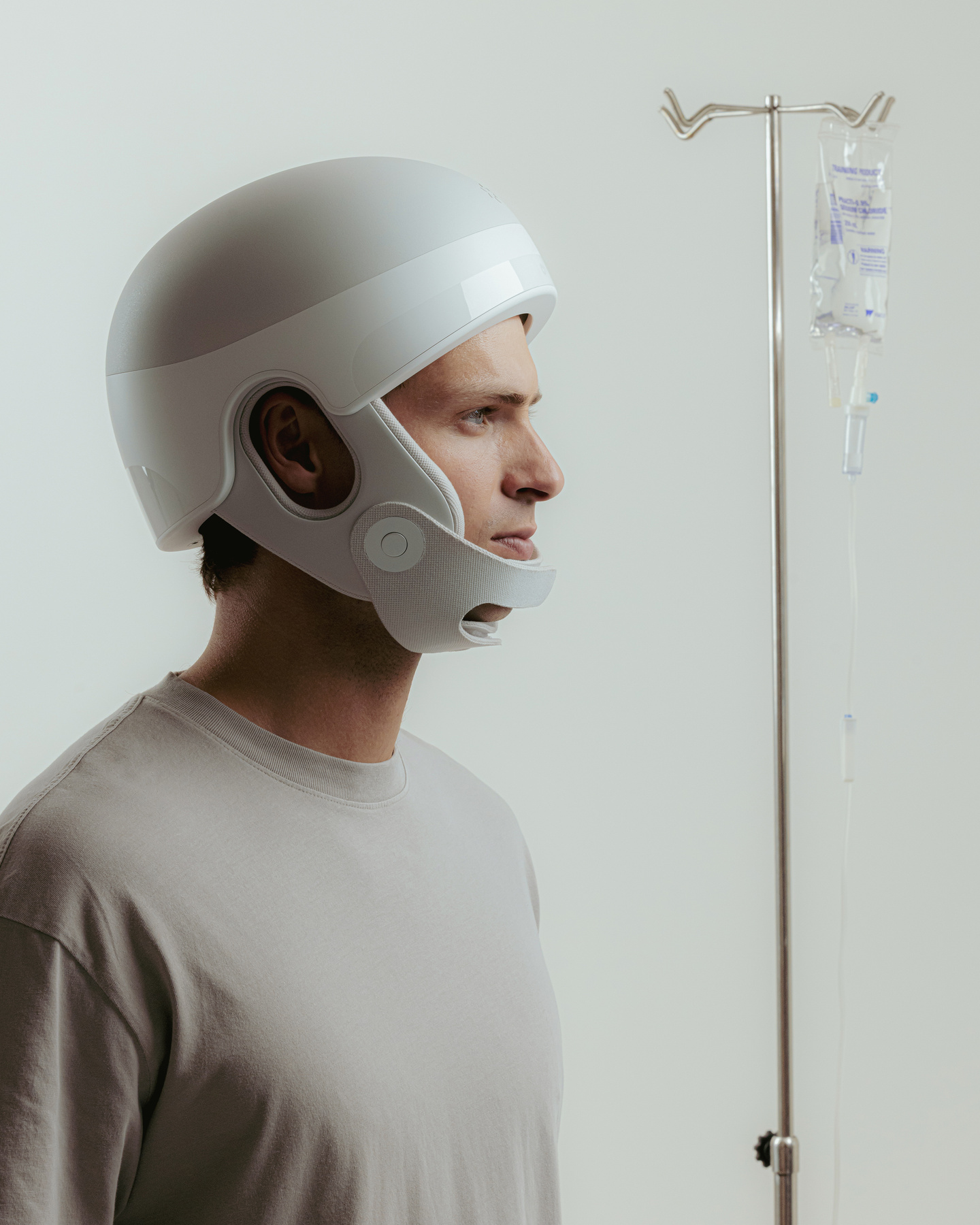 Man in profile wearing white medical headwear standing beside a medical drip pole