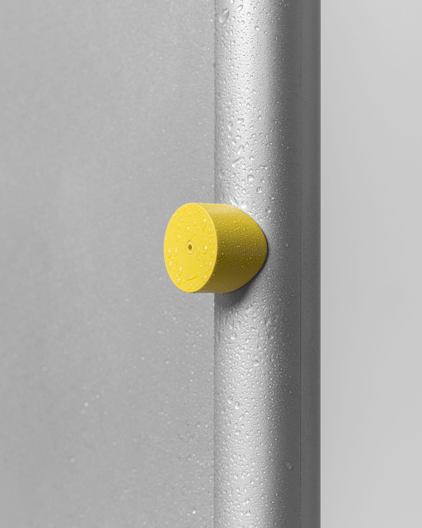 Yellow circular dial fixture mounted on a textured vertical pole