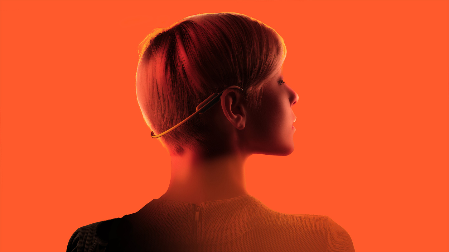 Profile view of a person wearing the Clay AI wearable neckband illuminated against a bright orange backdrop