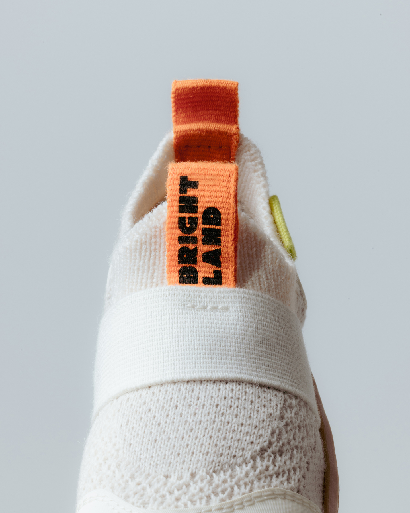 A close-up of a back of a shoe with an orange tag on a grey background.