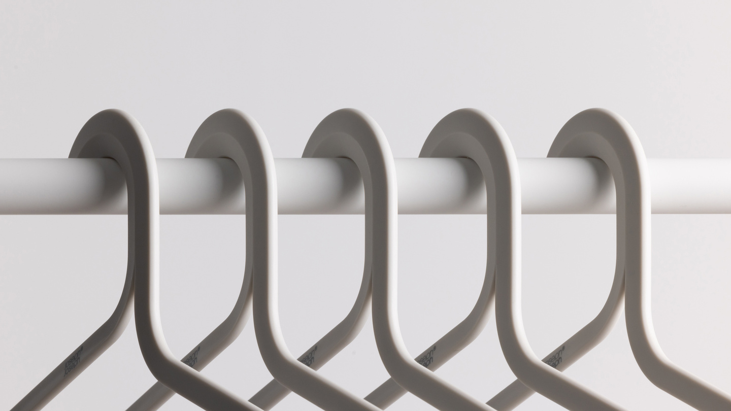 Row of grey coat hangers hanging on a white clothes rail