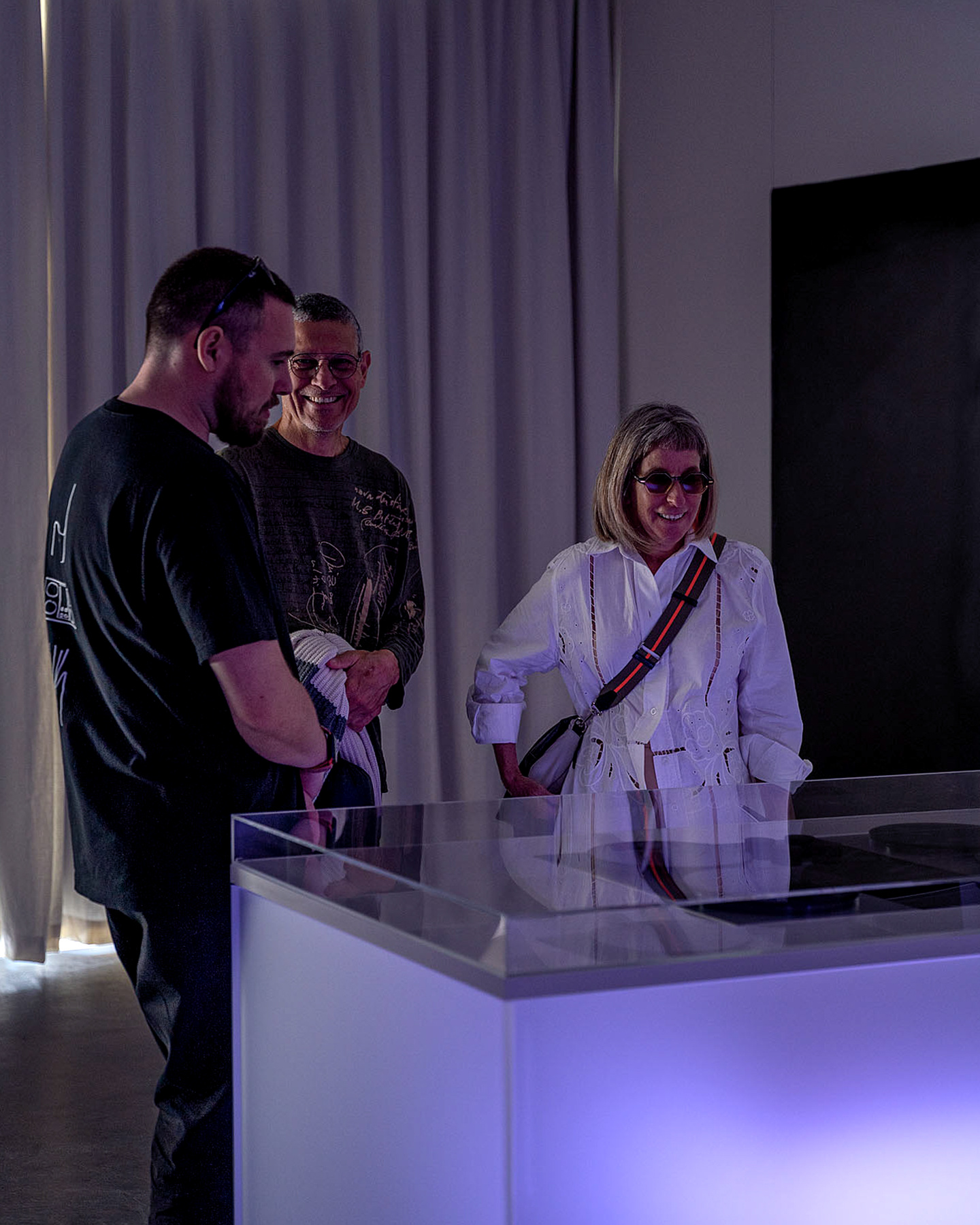 Visitors standing beside an illuminated exhibition counter examining products.