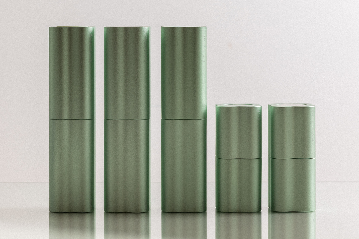 Five light green fluted skincare bottles arranged side by side