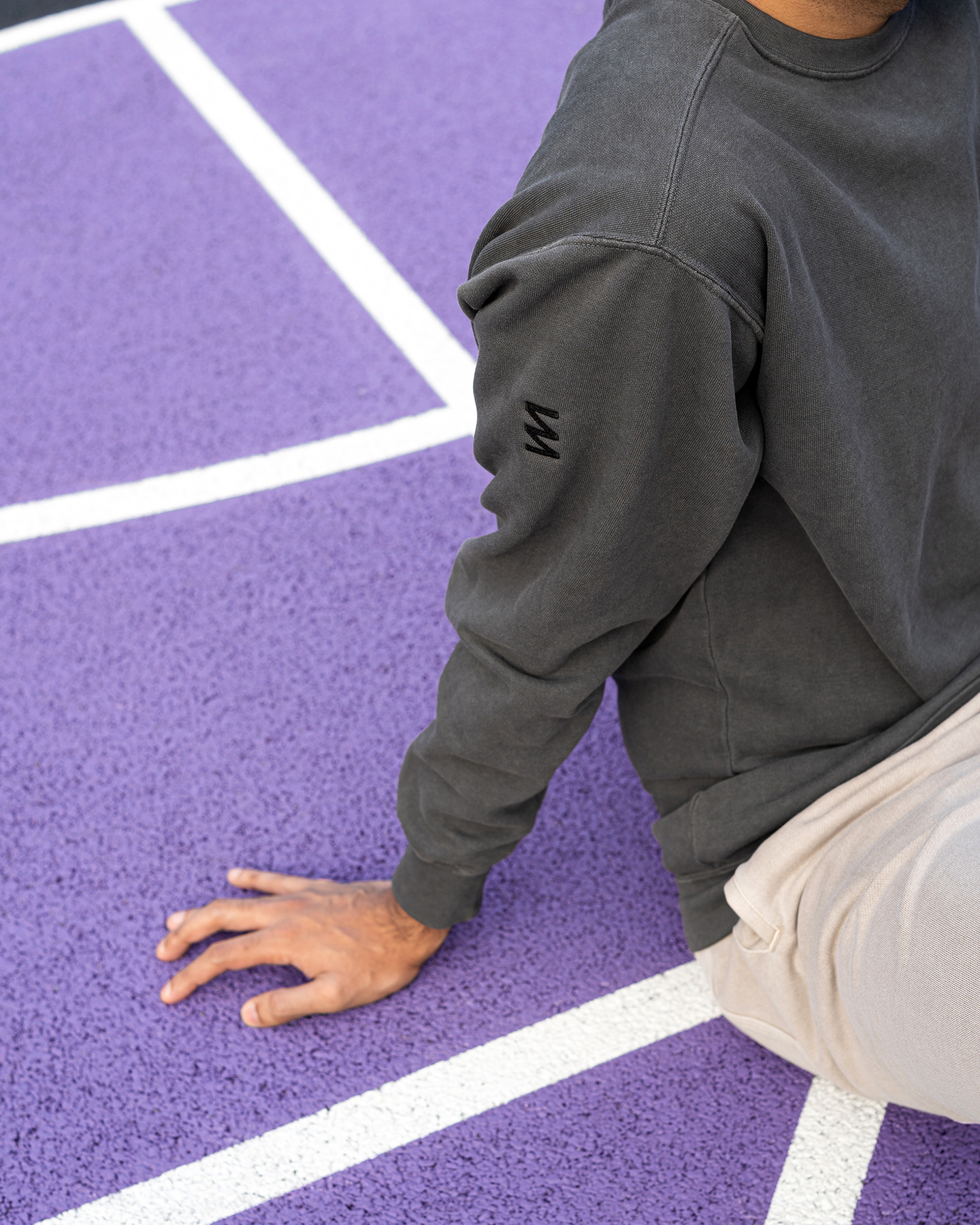 Inset photograph of a person sat on a colored sports court in branded sweater