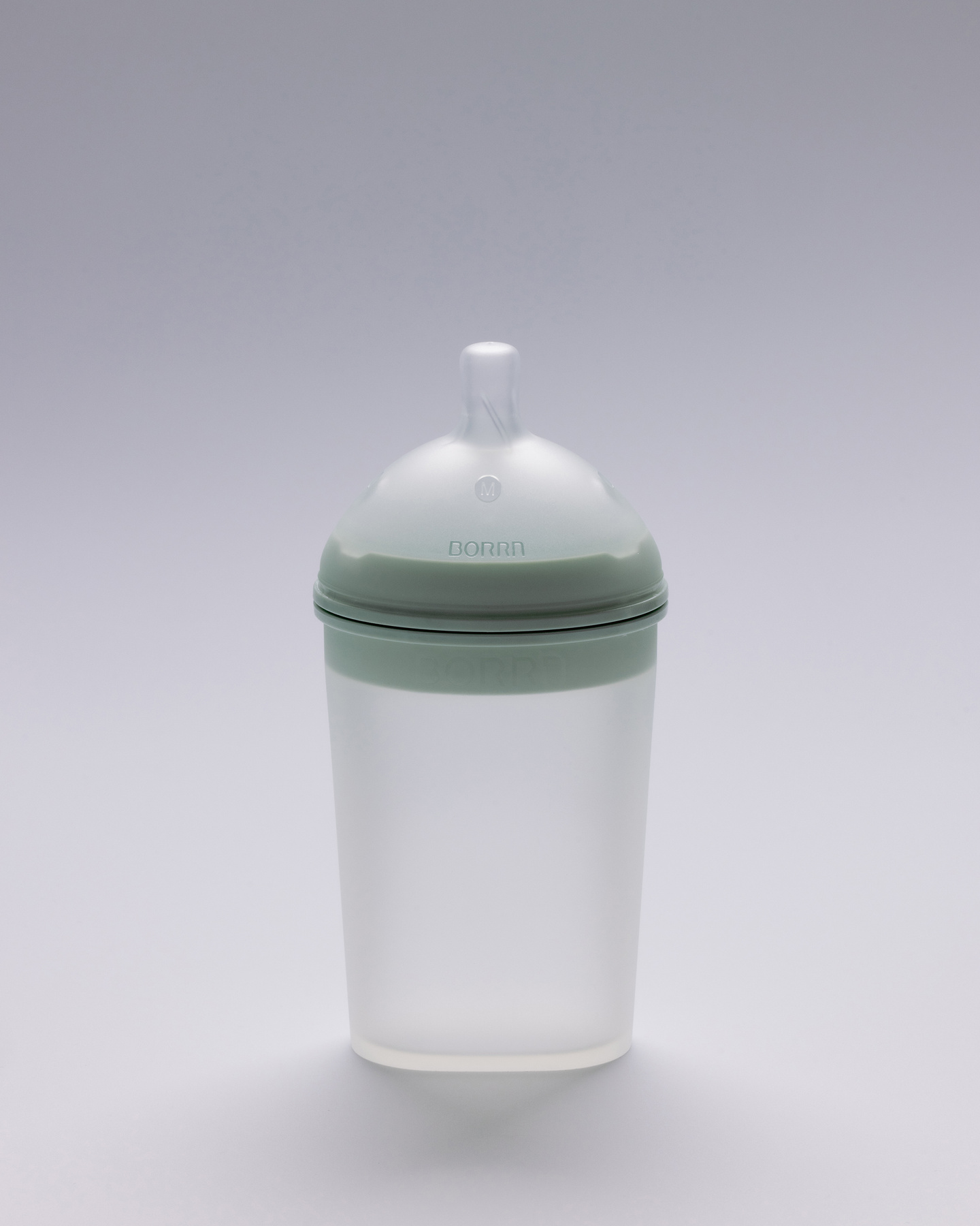 White silicone feeding bottle with a pale green collar against a plain backdrop.