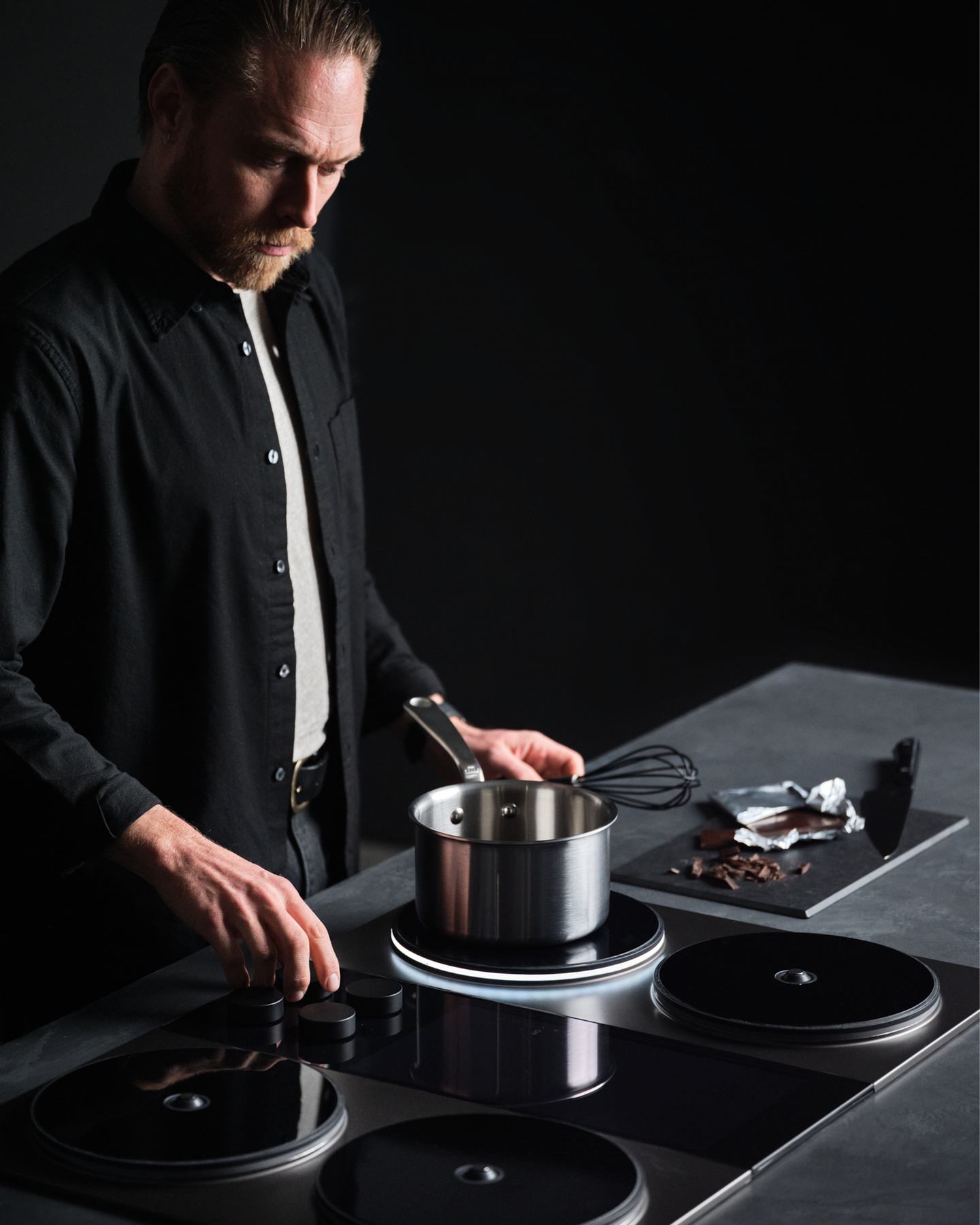 Chef using a pot while cooking on an induction stovetop in low light