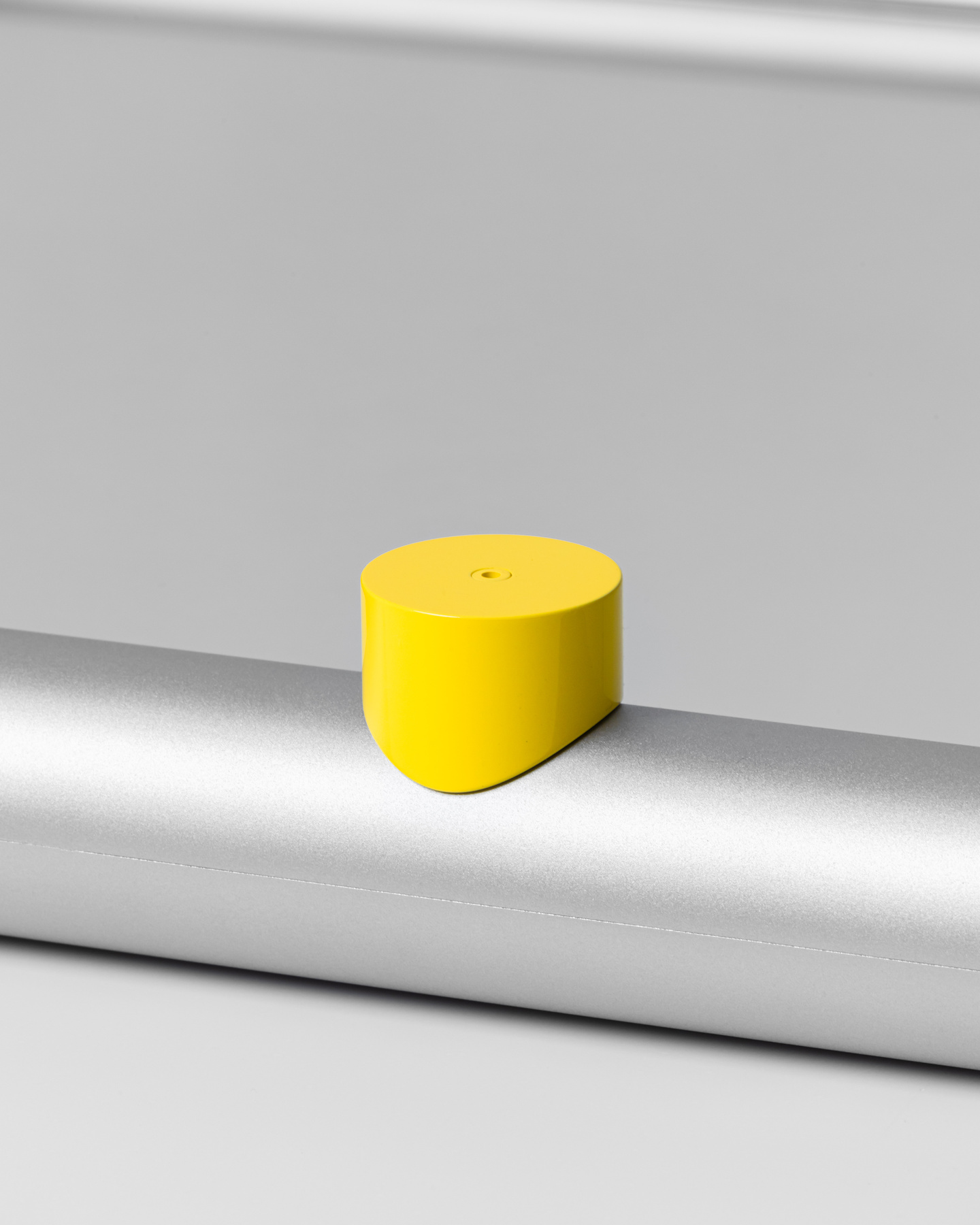 Small yellow circular adjustment knob attached to a light grey metal surface