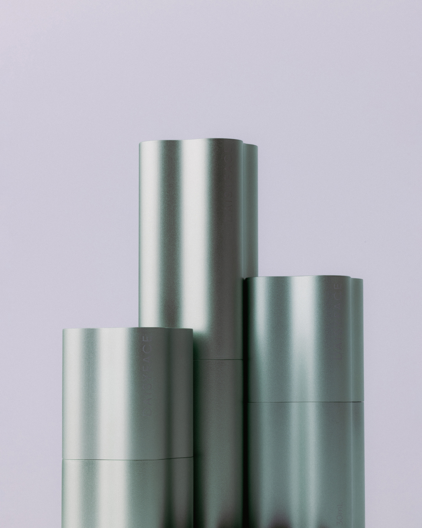 Three metallic skincare bottles in silver and grey tones