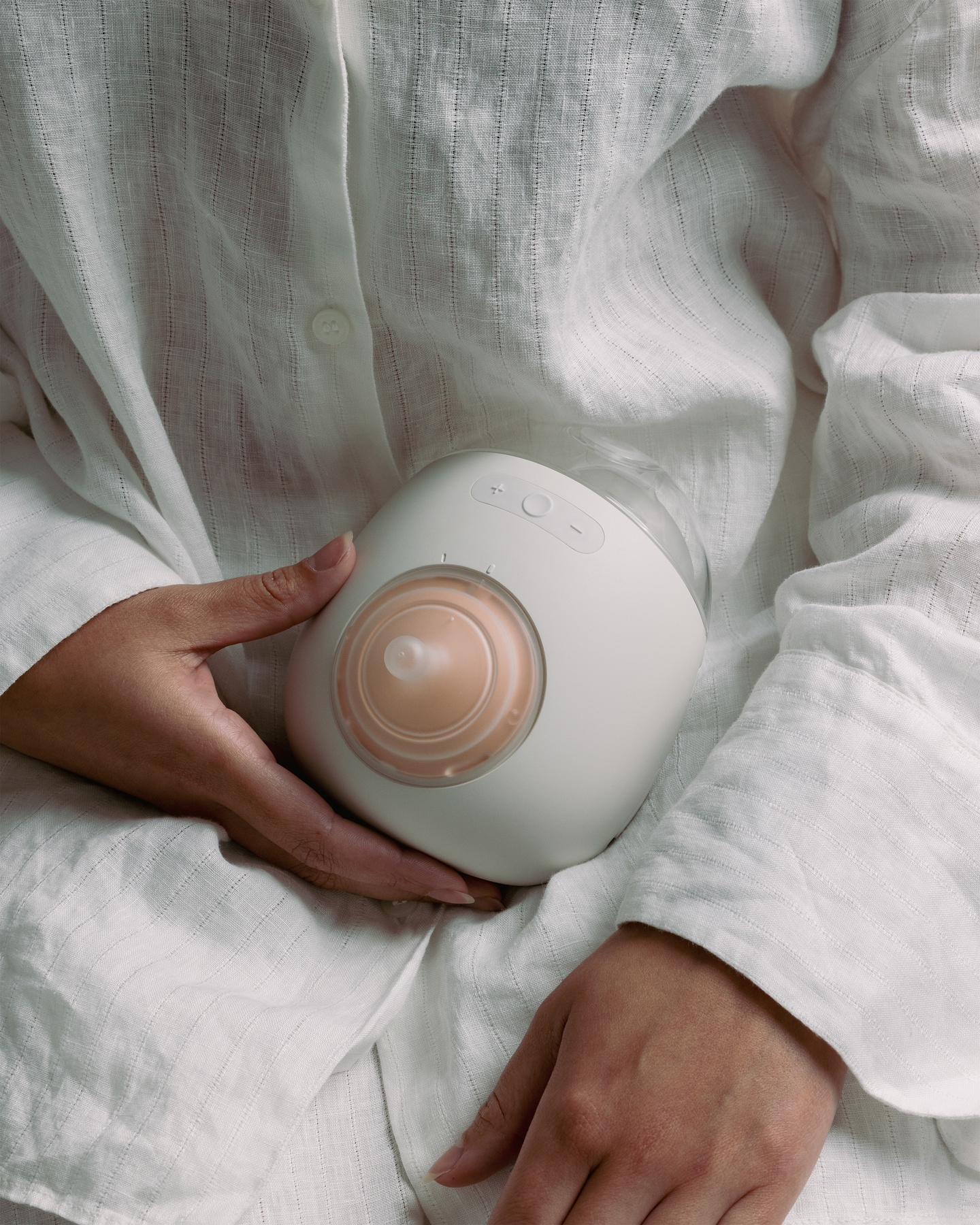 Woman in a white robe holding the assembled Avira smart breast pump.