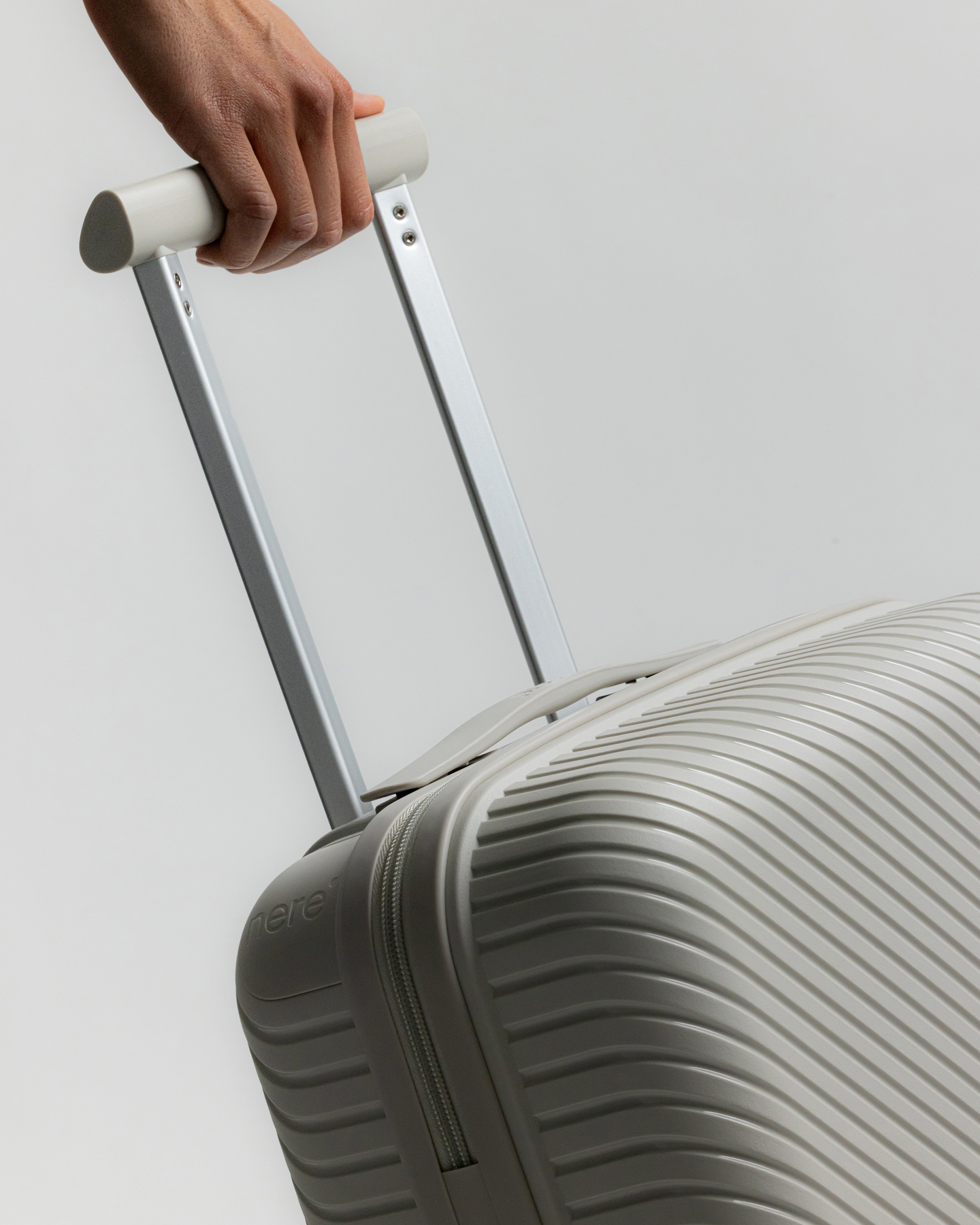 Hand extending the telescoping handle of a grey hardshell suitcase