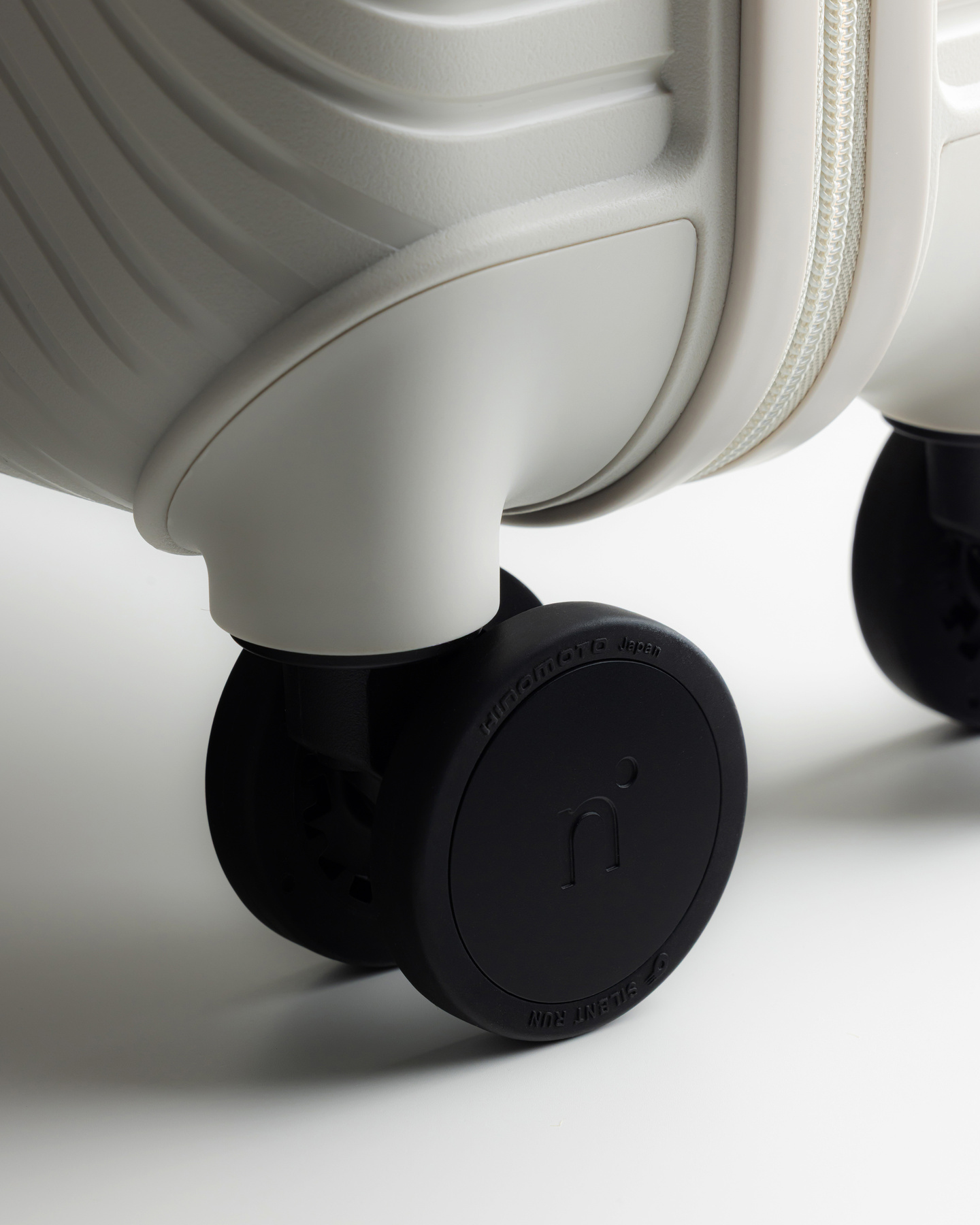 Close-up of a black caster wheel attached to a grey suitcase base