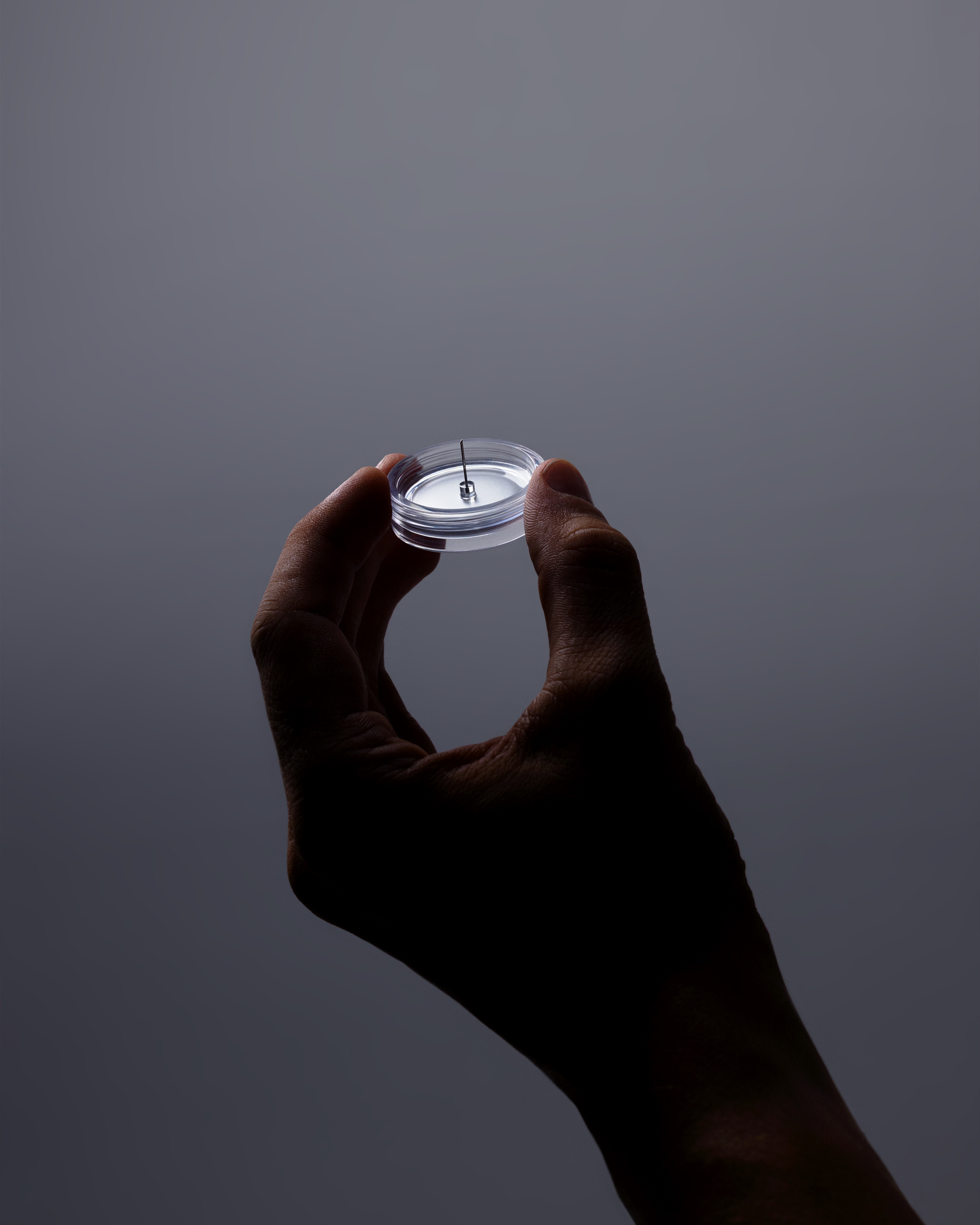 Close-up of a hand holding a small white circular wearable continuous glucose monitor sensor