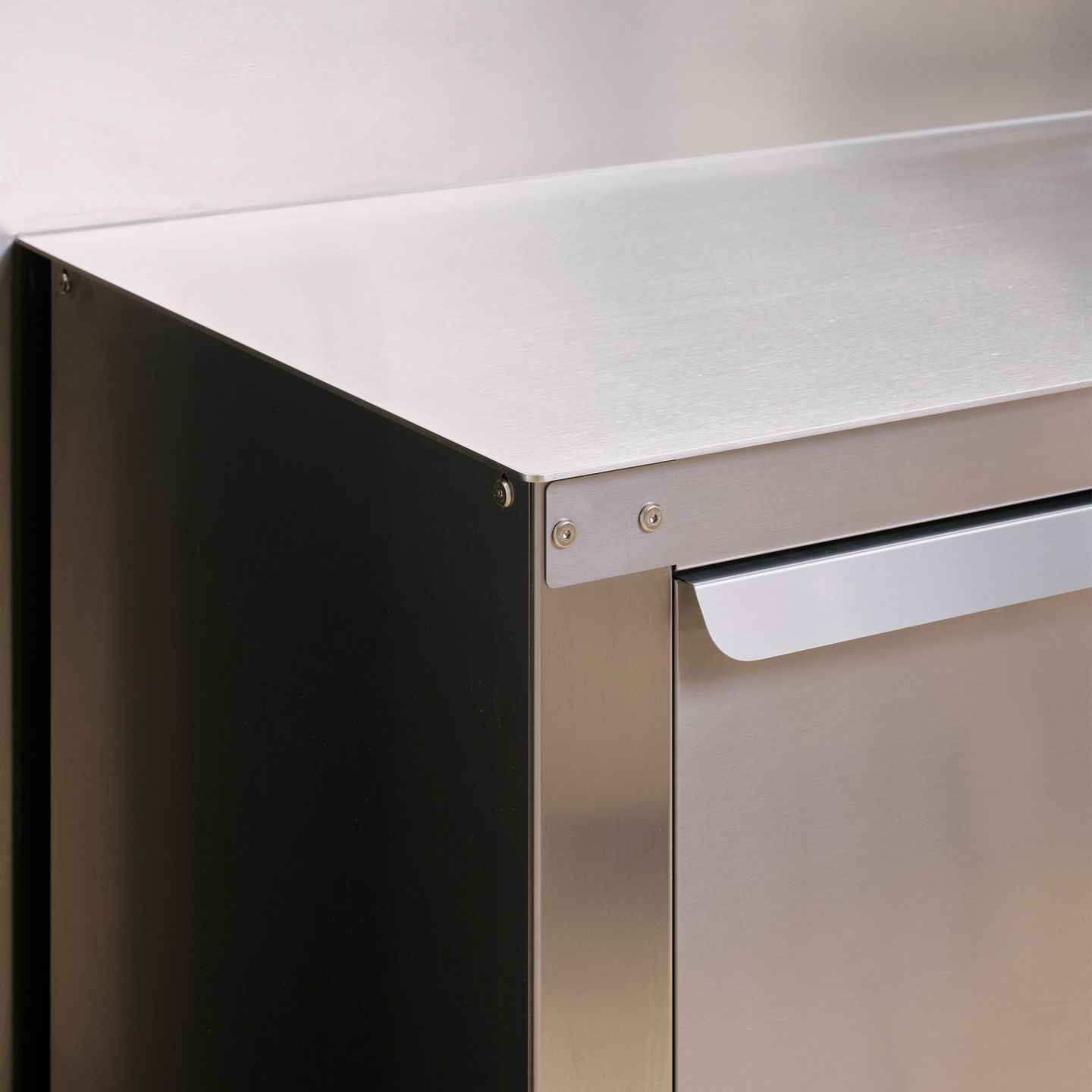 Close-up of a stainless steel kitchen cabinet corner featuring a sleek metal handle