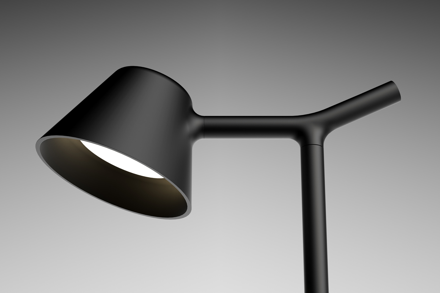 Matte black adjustable desk lamp head pointing downwards on grey gradient background