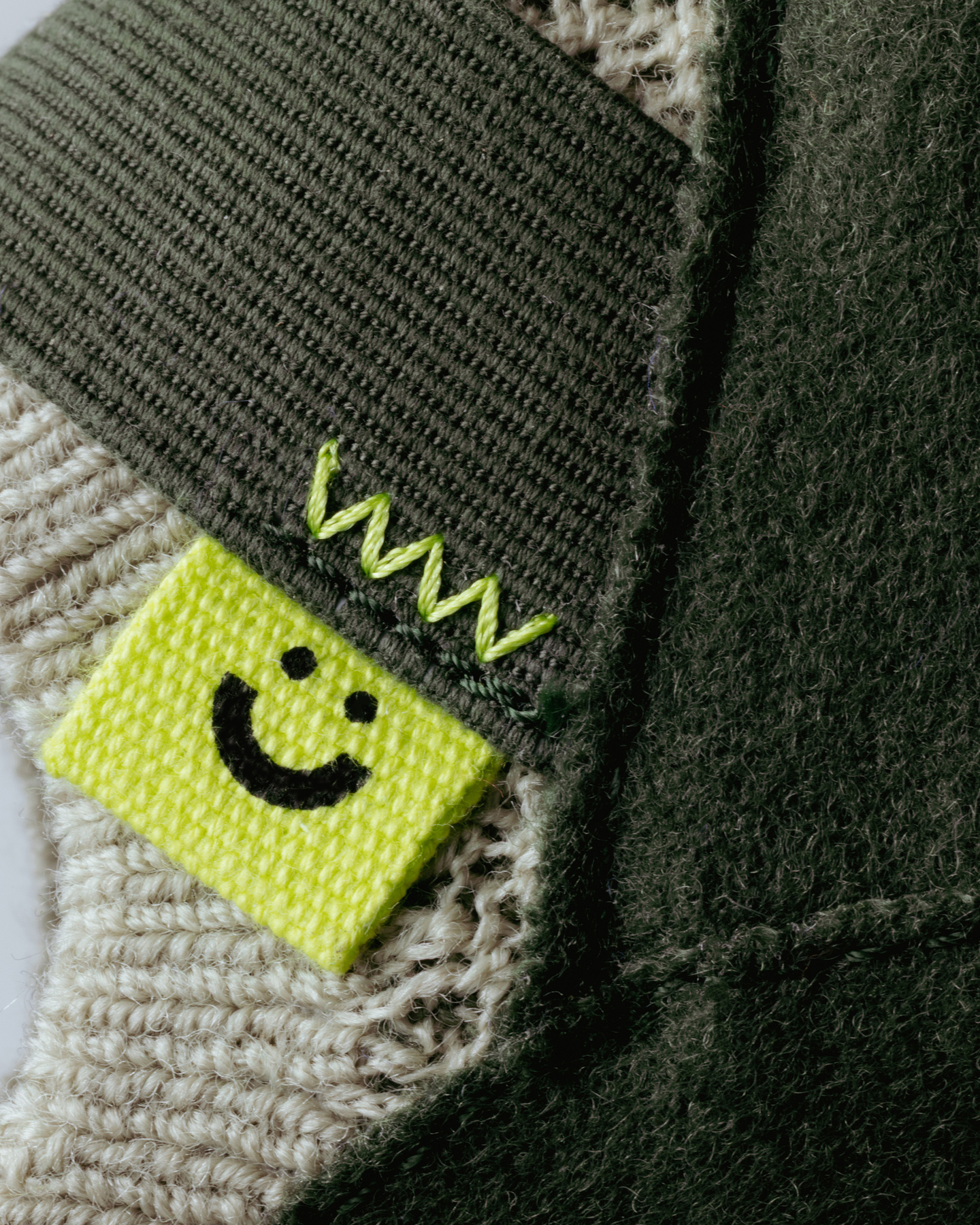 Close-up of green woven fabric showing a small yellow smiley brand tab.