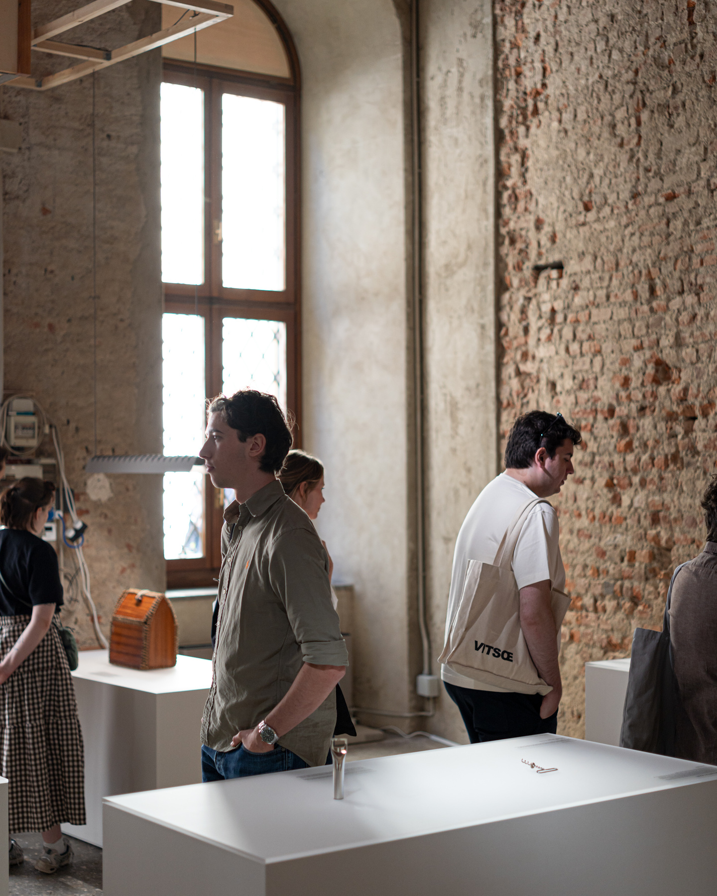 Visitors examining prototype objects near window inside exhibition room