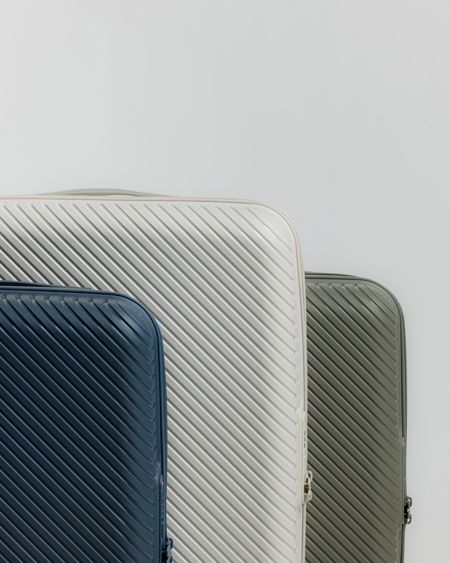 Blue, grey, and green hardshell suitcases standing side by side