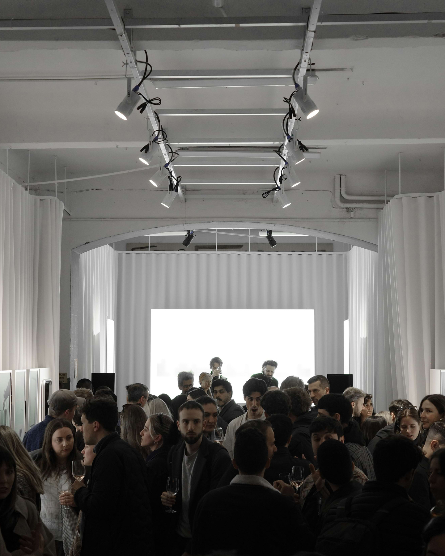 Visitors gathering in a brightly lit exhibition hall with hanging overhead lights