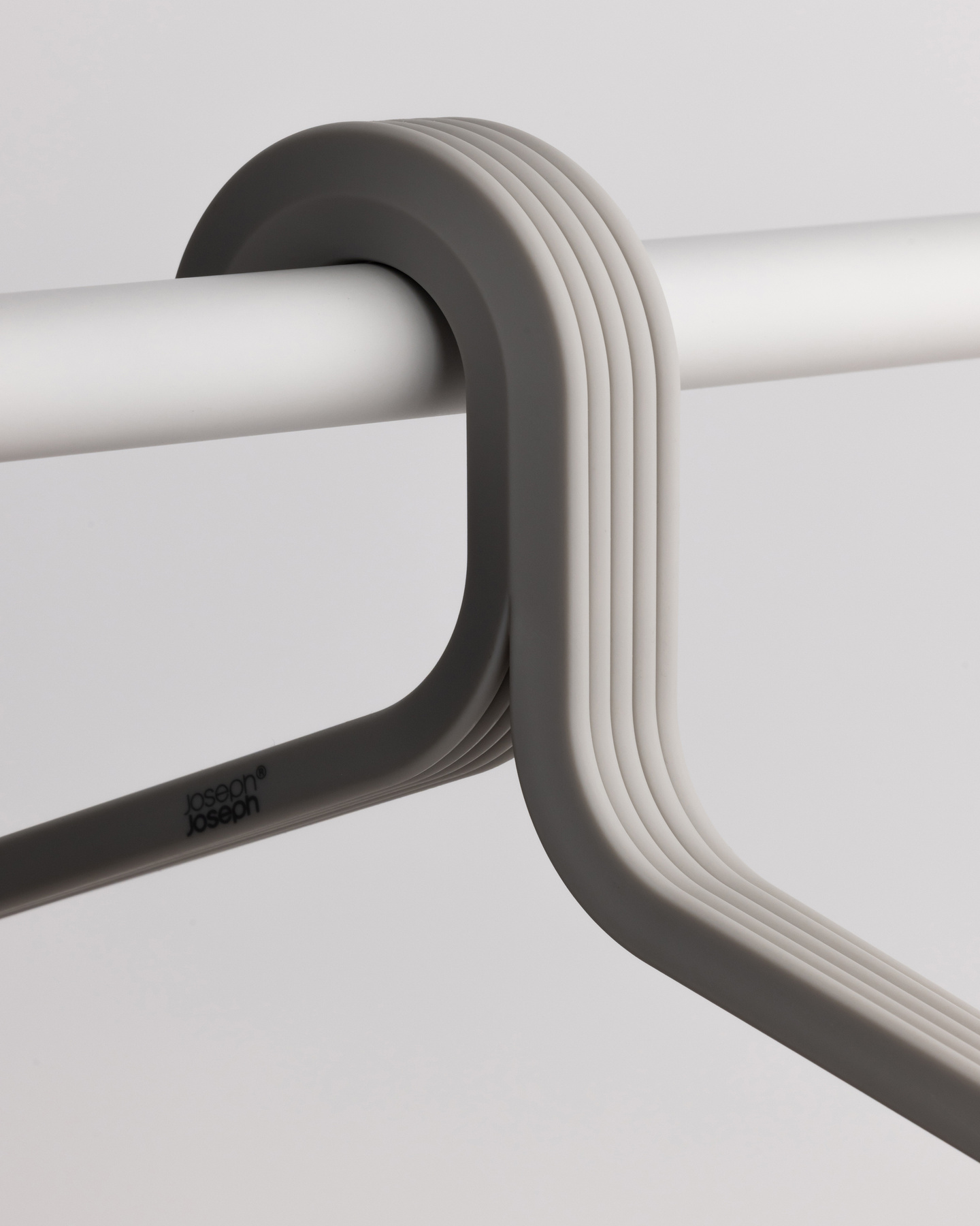 Close-up of a grey coat hanger neck hook seated on a white rail